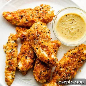 Everything Bagel Chicken Tenders arranged on a round plate and served with honey mustard dipping sauce