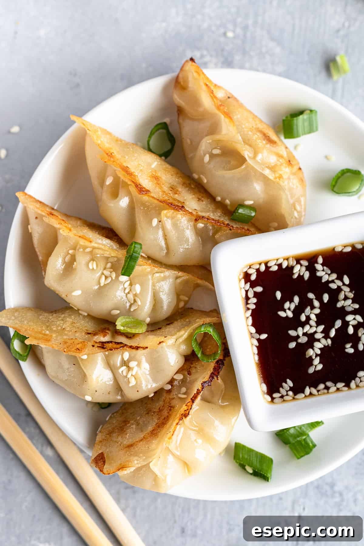 Crispy homemade chicken potstickers served on a white platter, garnished with green onions.
