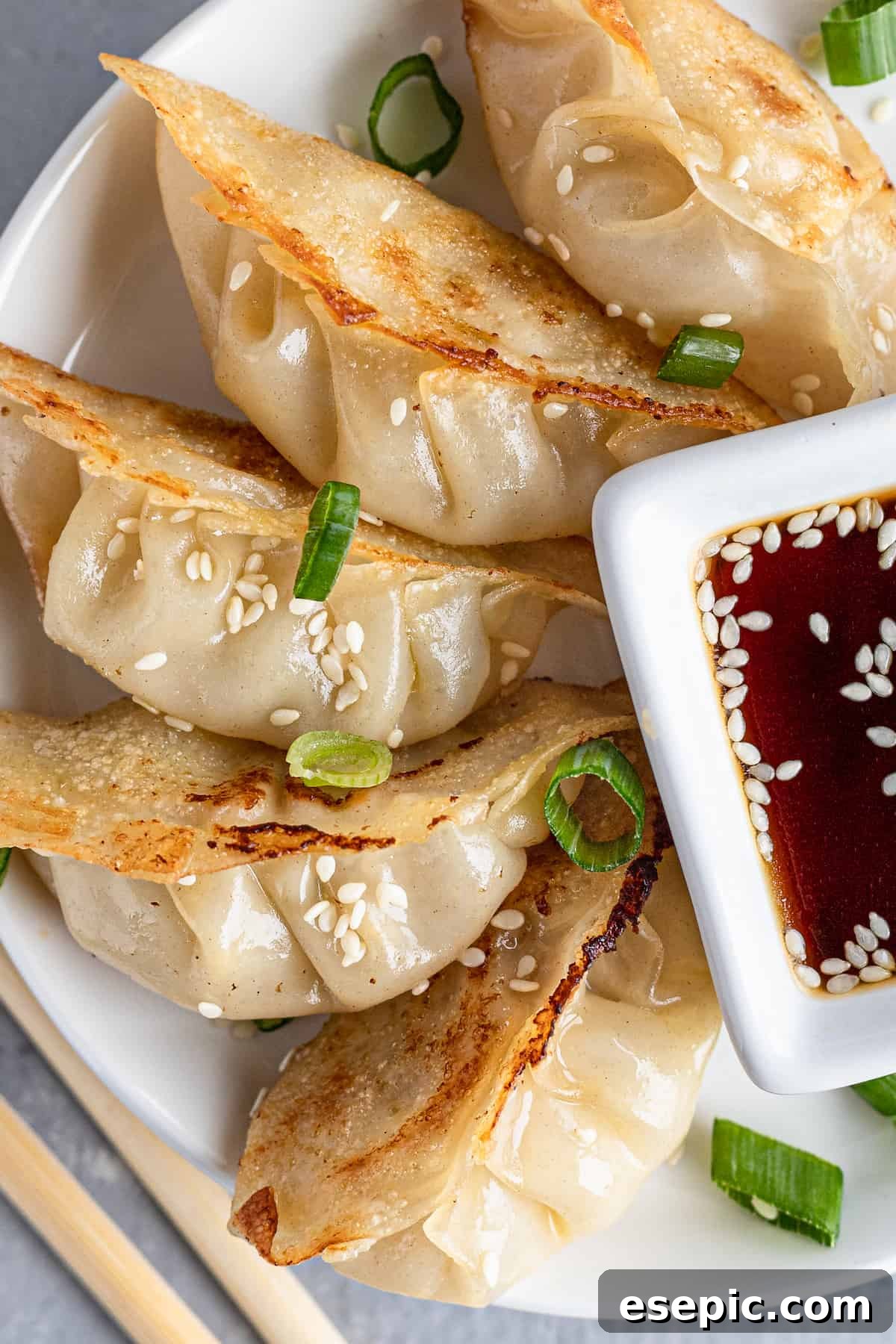 A close-up shot of perfectly cooked chicken potstickers on a plate, garnished with freshly diced scallions.