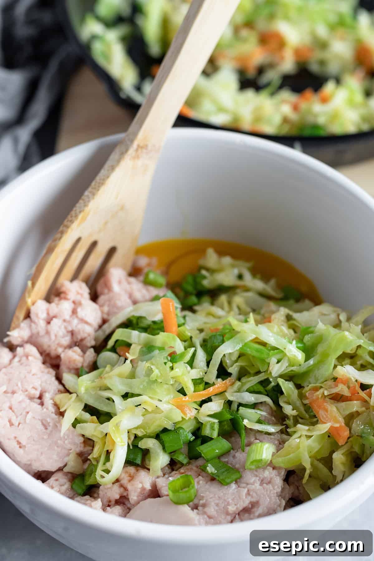 Cooked cabbage coleslaw and other potsticker filling ingredients assembled in a bowl, ready for dumpling assembly.