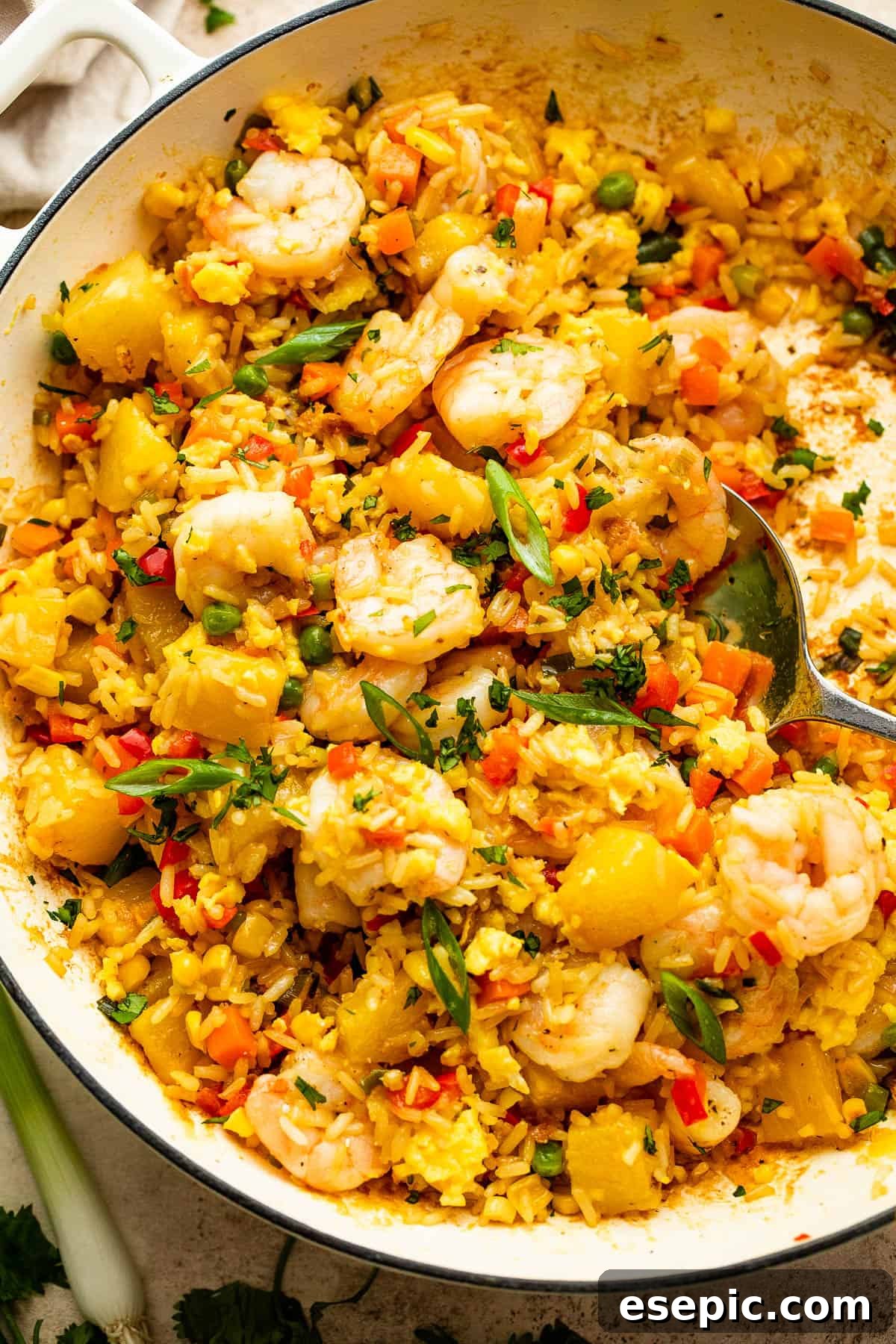 Tropical Pineapple Shrimp Fried Rice 2 White cast iron skillet with Shrimp Fried Rice and pineapple chunks, garnished with green onions.