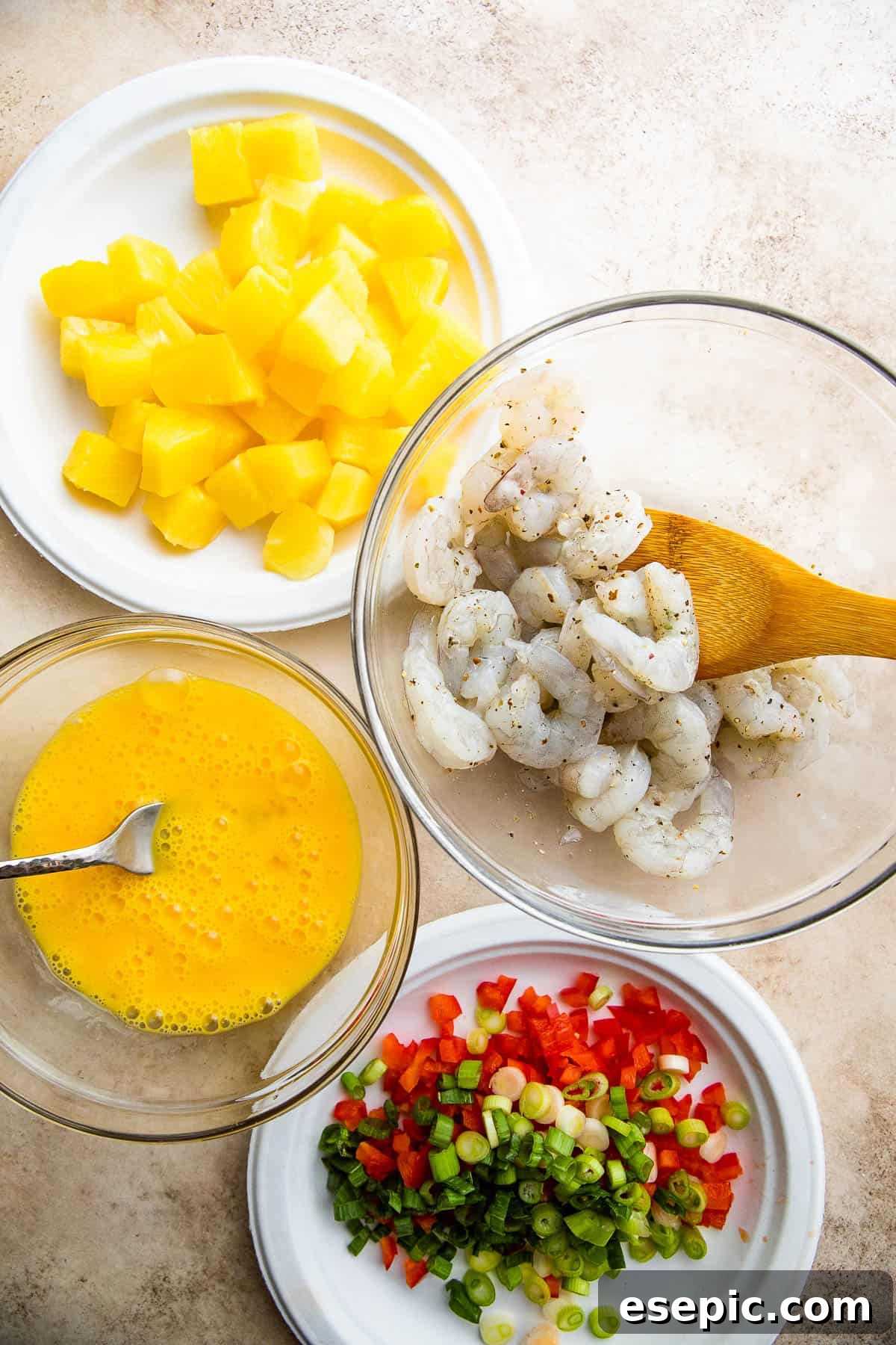 Tropical Pineapple Shrimp Fried Rice 4 Bowls filled with individual shrimp fried rice ingredients laid out on a wooden surface.