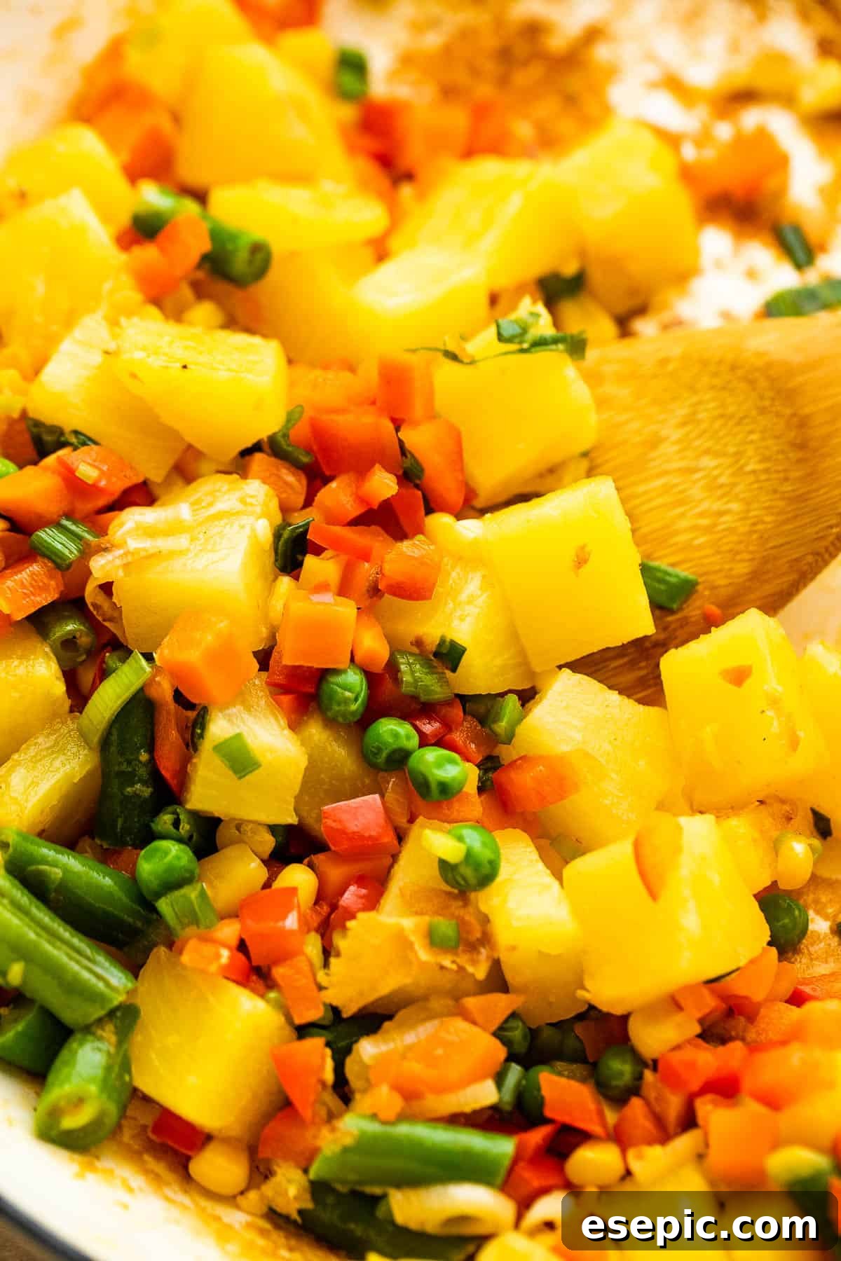 Tropical Pineapple Shrimp Fried Rice 5 Pineapple chunks cooking with mixed vegetables in a hot wok, showing vibrant colors.