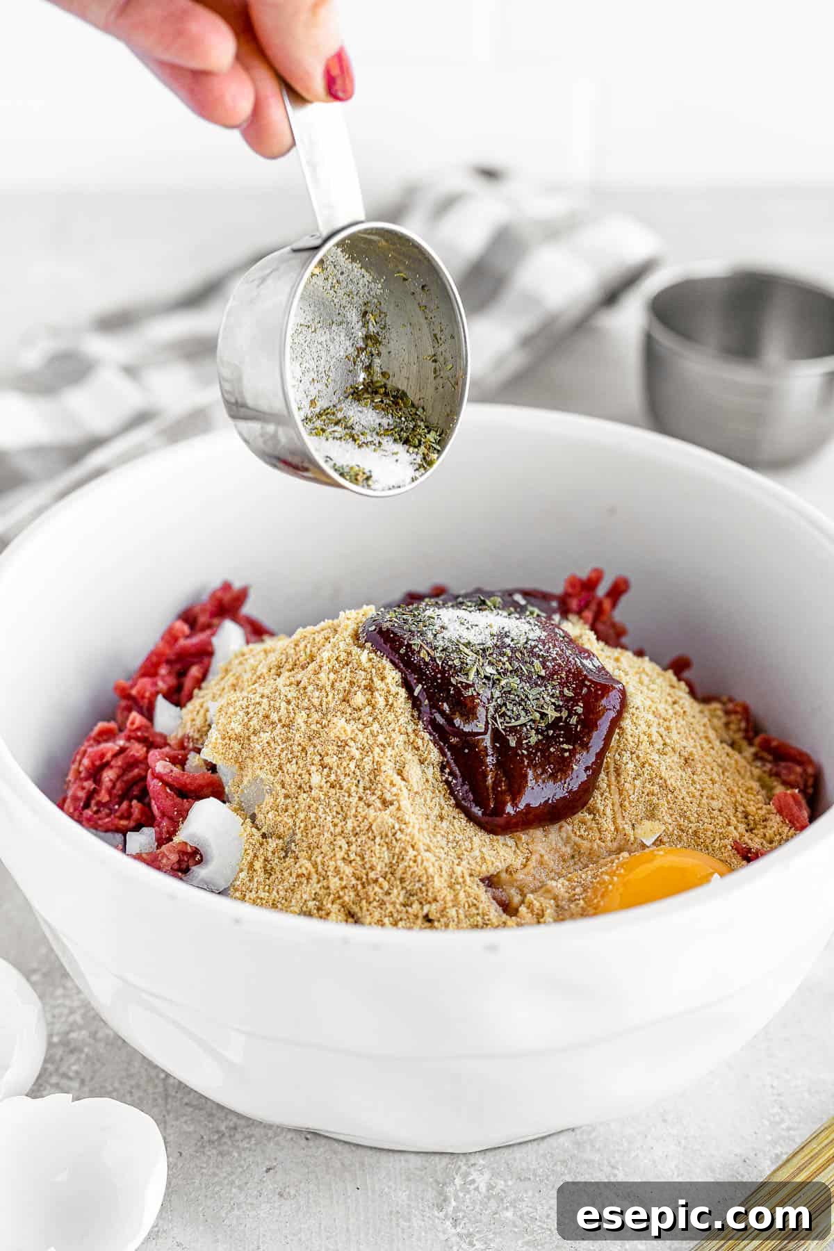 A family-friendly classic, this easy meatloaf recipe gets extra flavor from barbecue sauce, plenty of garlic, and Italian seasoning. A Bowl of the Meatloaf Mixture Beside a Glass Pan on a Gray Surface