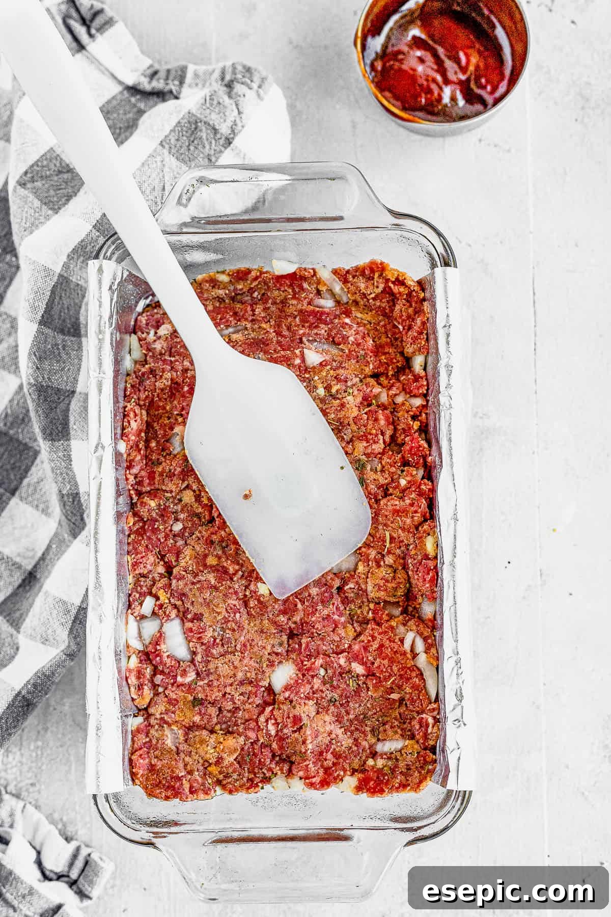 A family-friendly classic, this easy meatloaf recipe gets extra flavor from barbecue sauce, plenty of garlic, and Italian seasoning. A Spatula Spreading the Meatloaf Mixture Into a Foil-Lined Pan