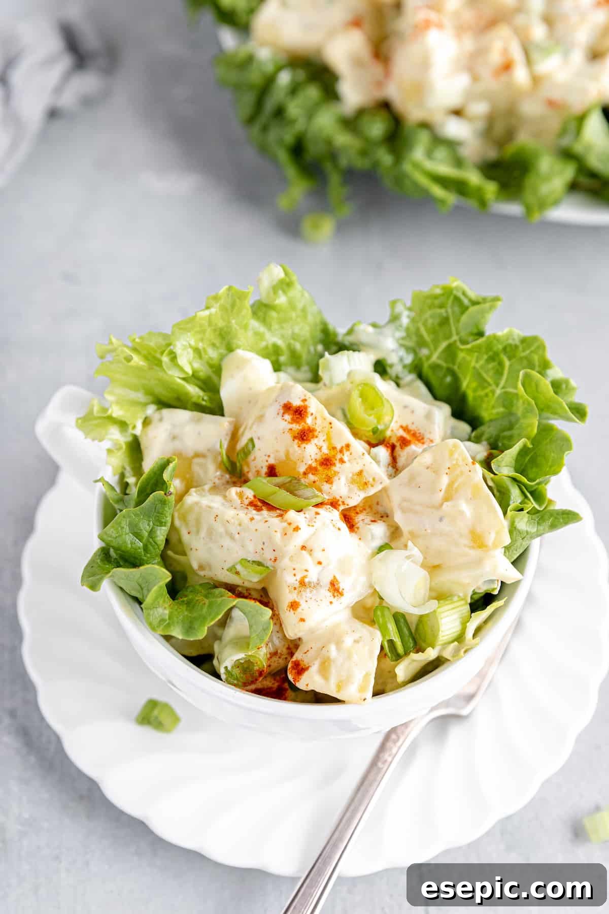 A Close-Up Shot of American Classic Potato Salad Served in a Large Cup, Garnished with Fresh Lettuce Leaves