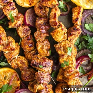 Five Shawarma Grilled Chicken Skewers on a Metal Pan with Onions, Lemon Slices and More