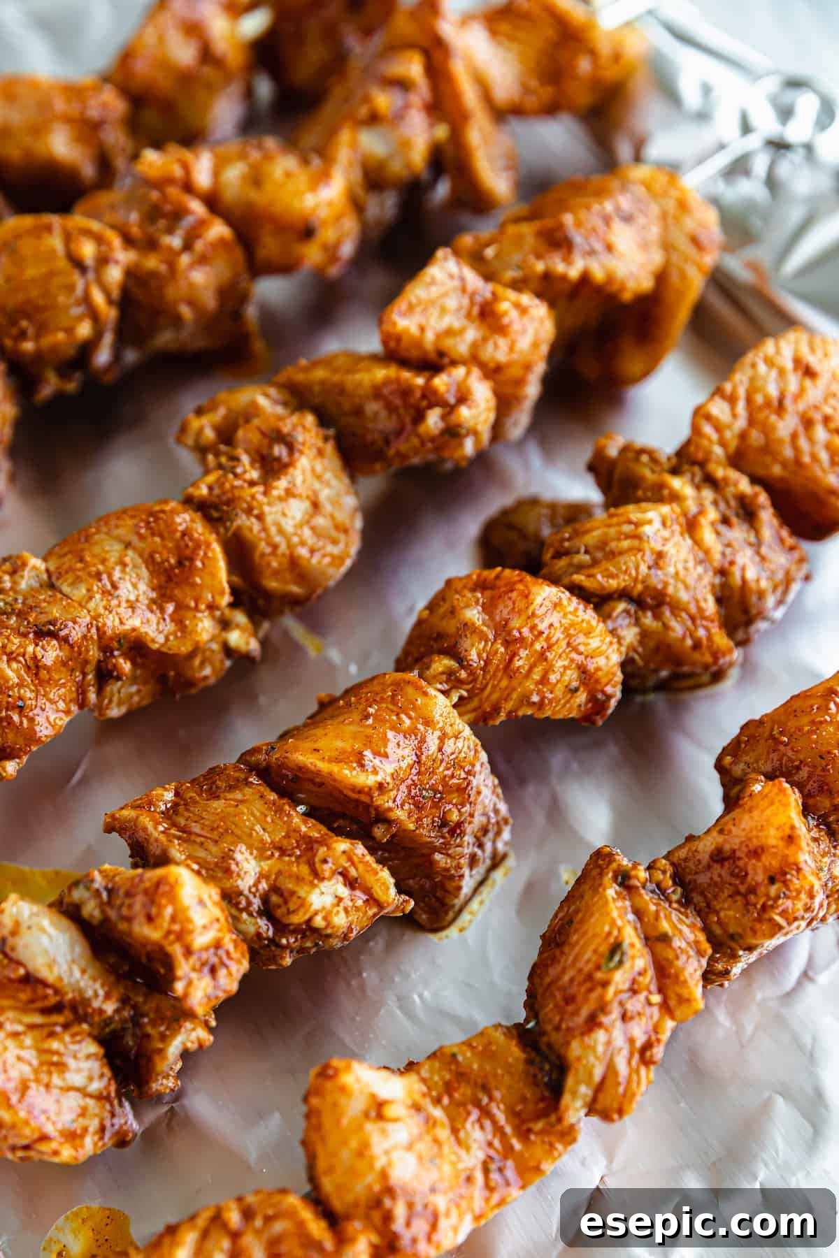 Five Freshly Grilled Shawarma Chicken Skewers Lined Up on a Sheet of Aluminum Foil