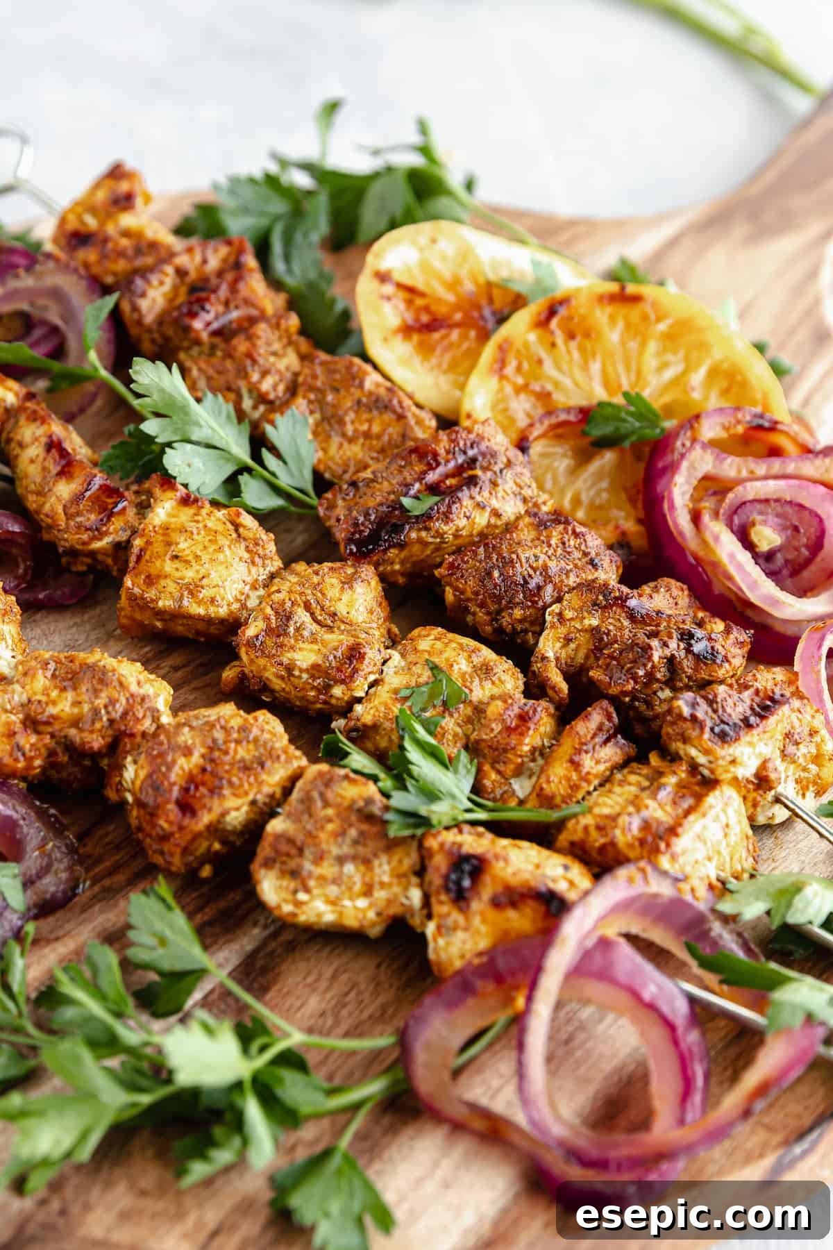 A Cutting Board on a Table Holding Onions, Lemon Slices and Shawarma Grilled Chicken Skewers