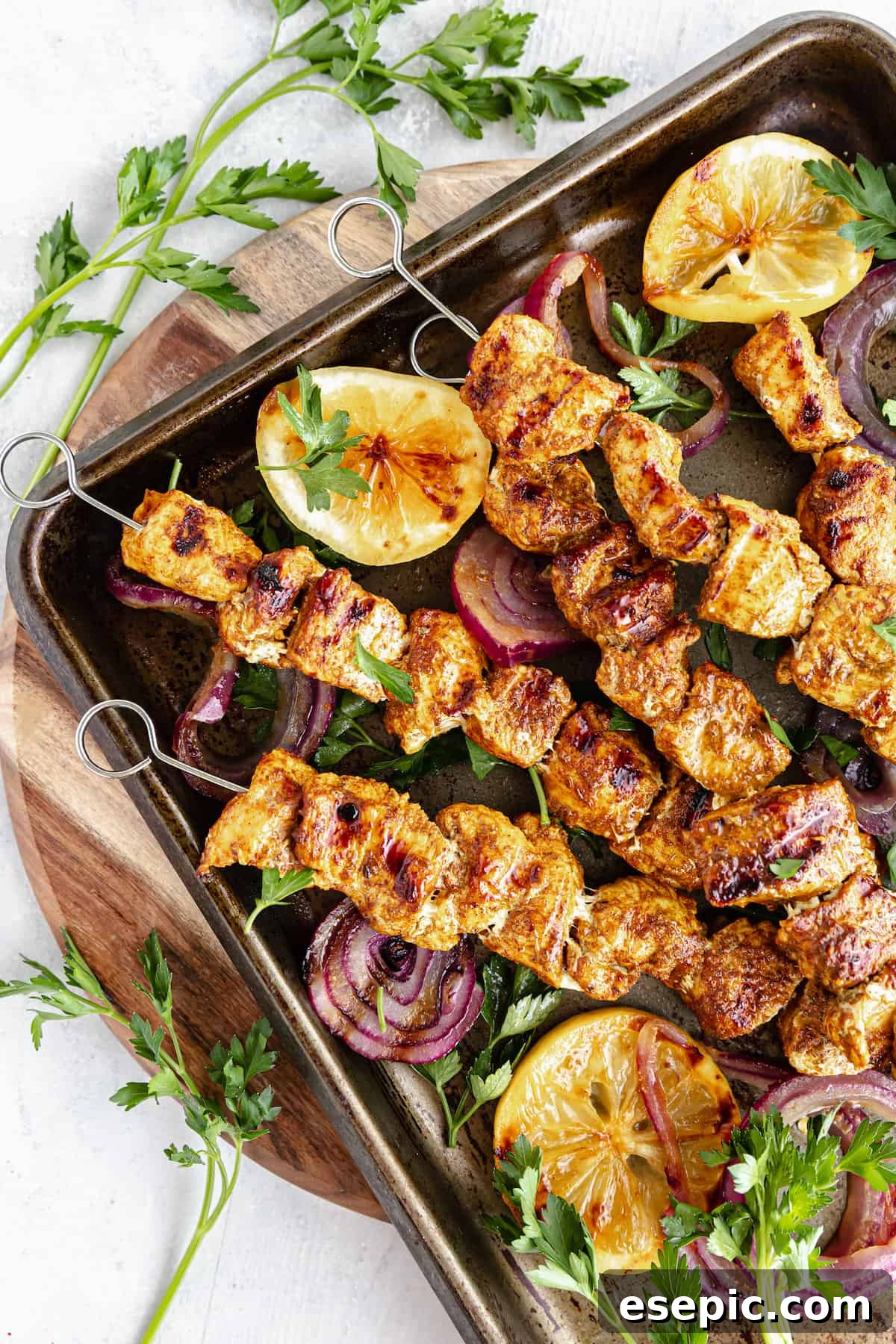 Grilled Chicken Skewers in a Pan on Top of a Round, Wooden Cutting Board