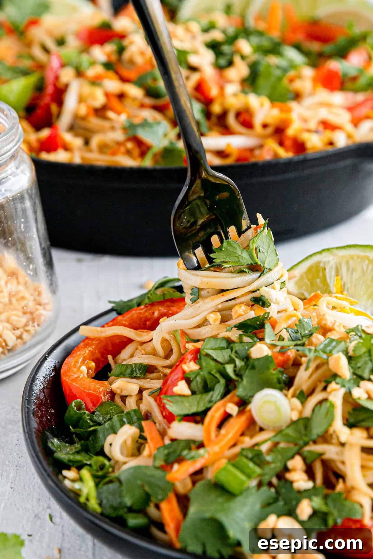 A Close-Up Shot of a Fork Digging Into a Plate of Pad Thai, highlighting the noodles and various toppings.