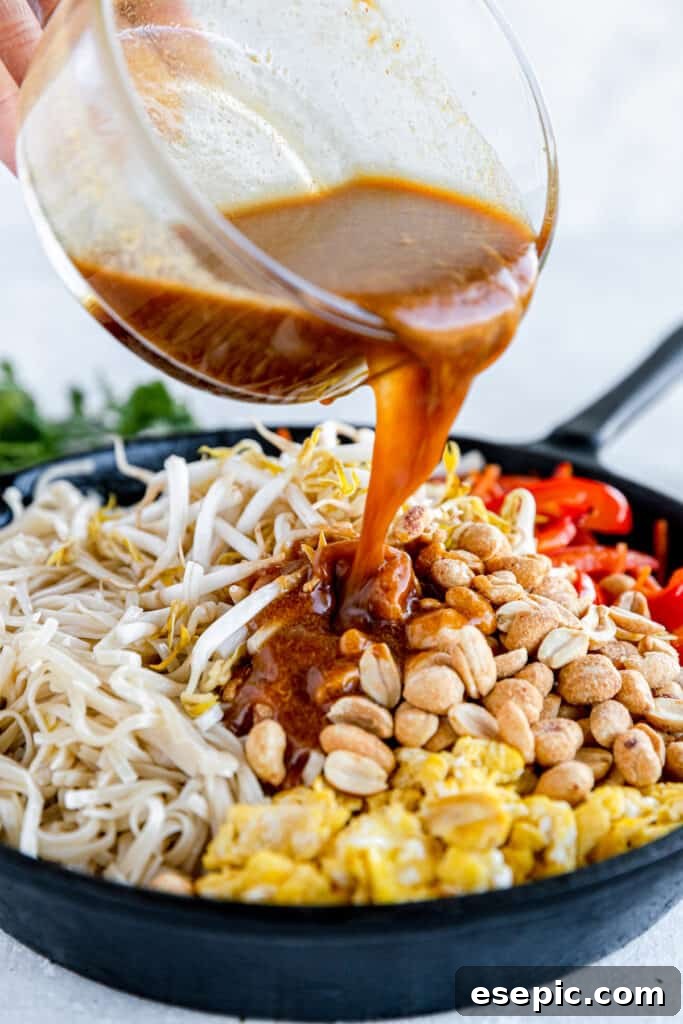 Pad Thai Sauce Being Poured Over the Skillet of Prepared Pad Thai, creating a mouth-watering aroma.
