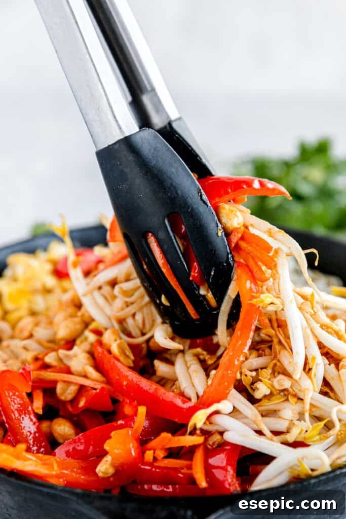 The Prepared Veggies and Nuts for Pad Thai Being Mixed with a Pair of Tongs, ensuring even coating.