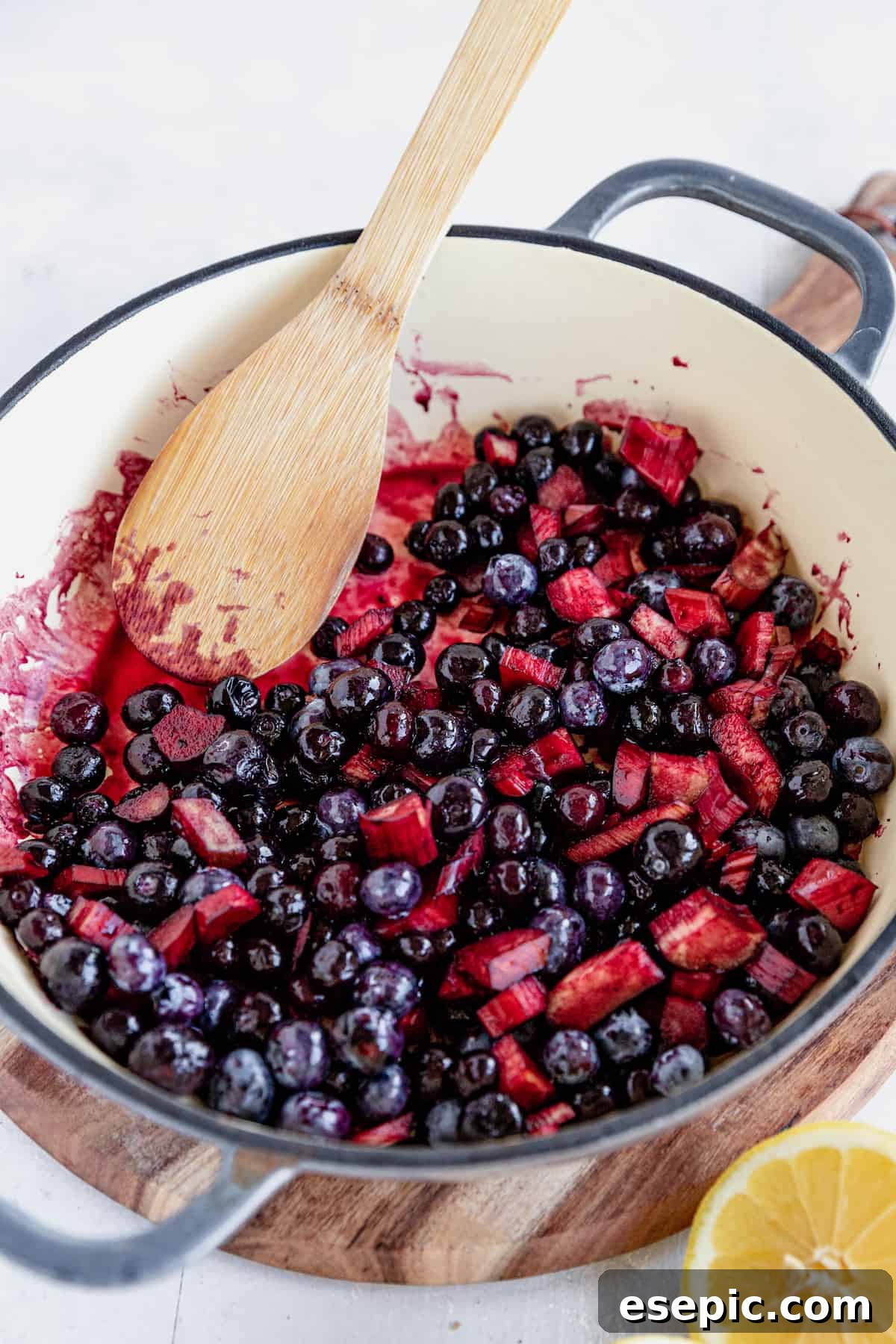 Golden Blueberry Rhubarb Delight 6 The Filling for Blueberry Rhubarb Cobbler in a Skillet Being Mixed with a Wooden Spoon