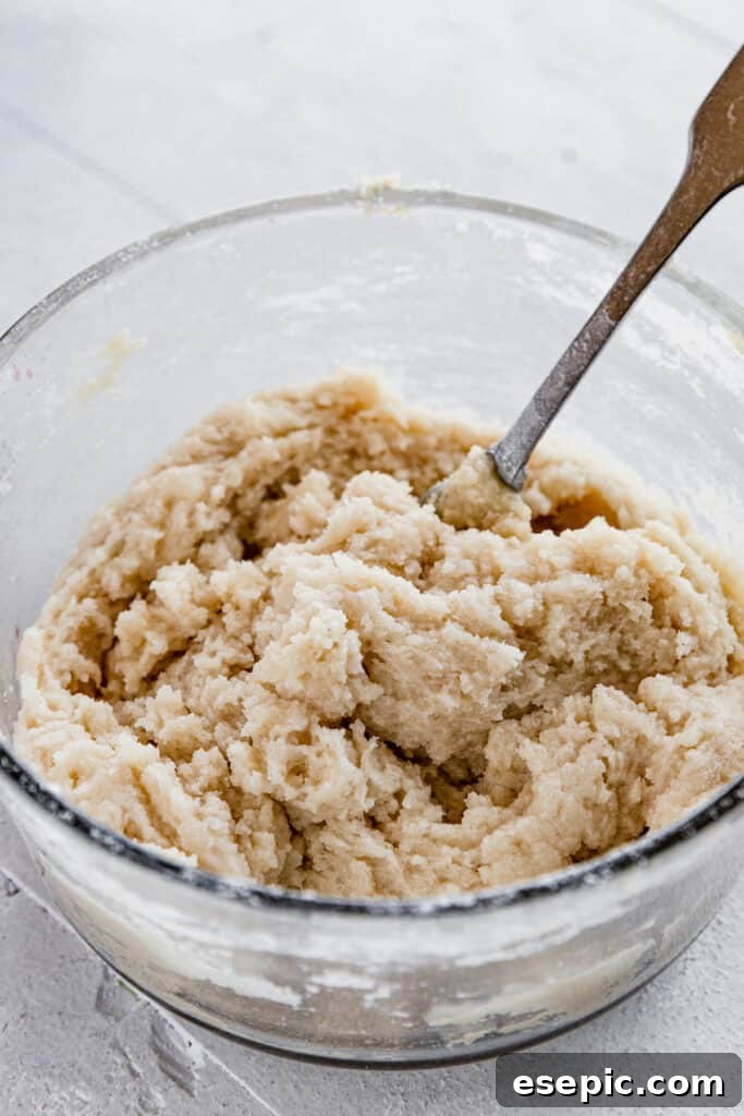 The Dough for the Topping of the Crisp in a Glass Bowl with a Metal Spoon, showing the sandy texture