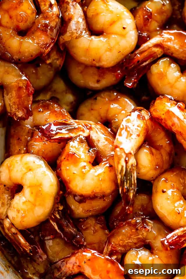 Honey Garlic Shrimp: A quick, easy, and incredibly flavorful shrimp recipe cooked in one skillet with just 5 ingredients in 20 min! Close-up shot of raw shrimp marinating in a honey garlic soy sauce mixture in a small bowl, showcasing the rich color of the marinade.