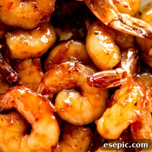 Picture of cooked honey garlic shrimp, garnished with fresh herbs and a vibrant glaze.