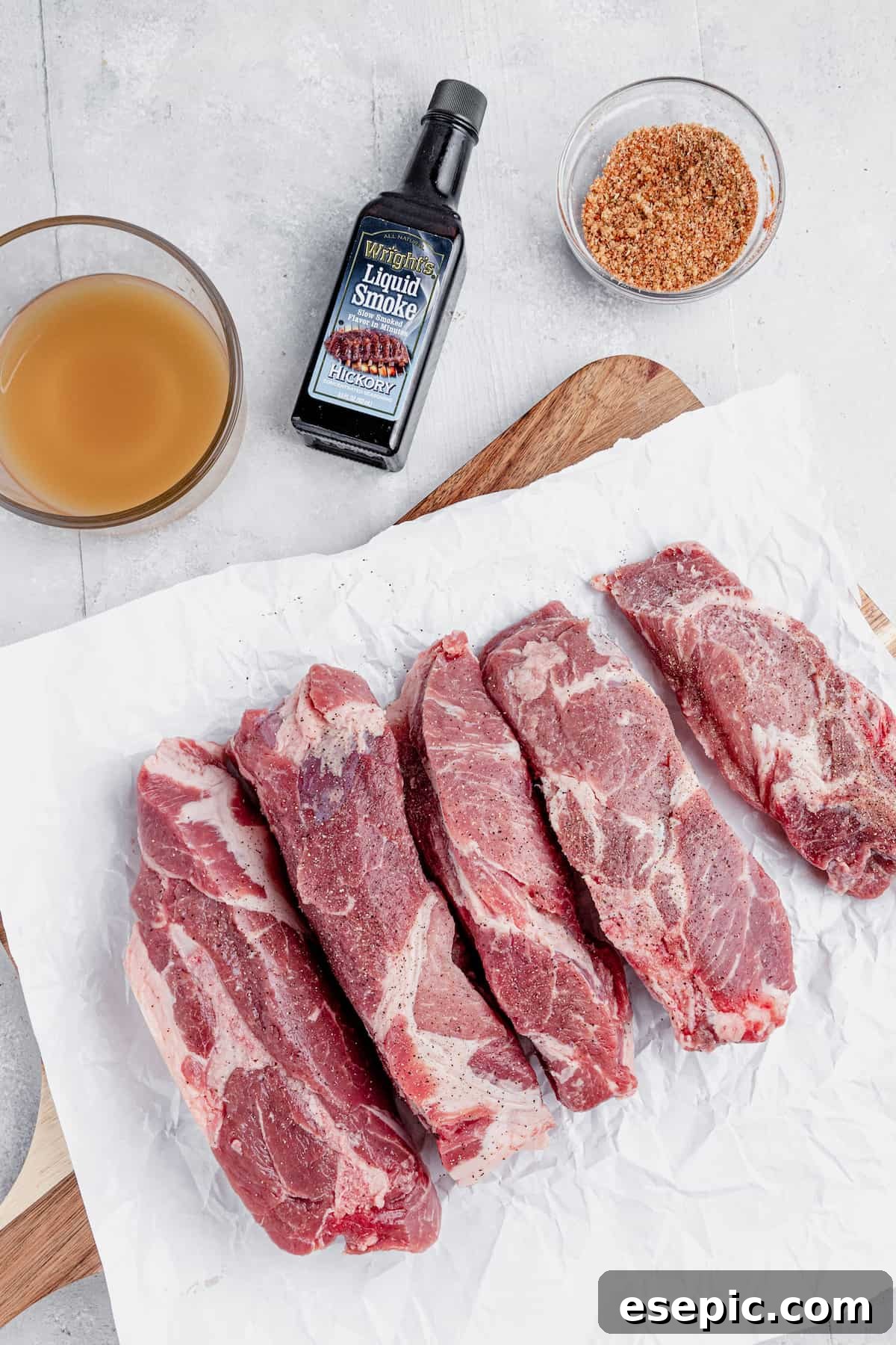 Unccoked Pork Ribs, a Bottle of Liquid Smoke and More of the Rib Ingredients on a Countertop