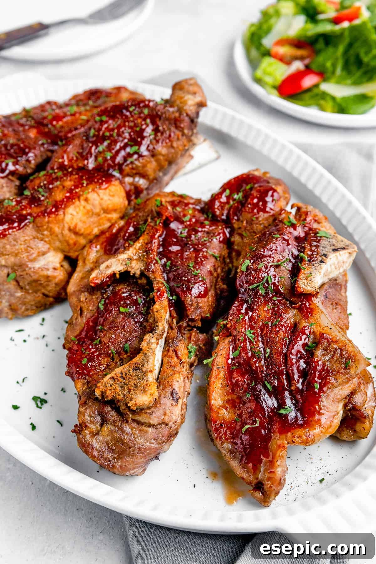 side shot of Instant Pot Ribs on a White Serving Platter with a Small Salad in the Background