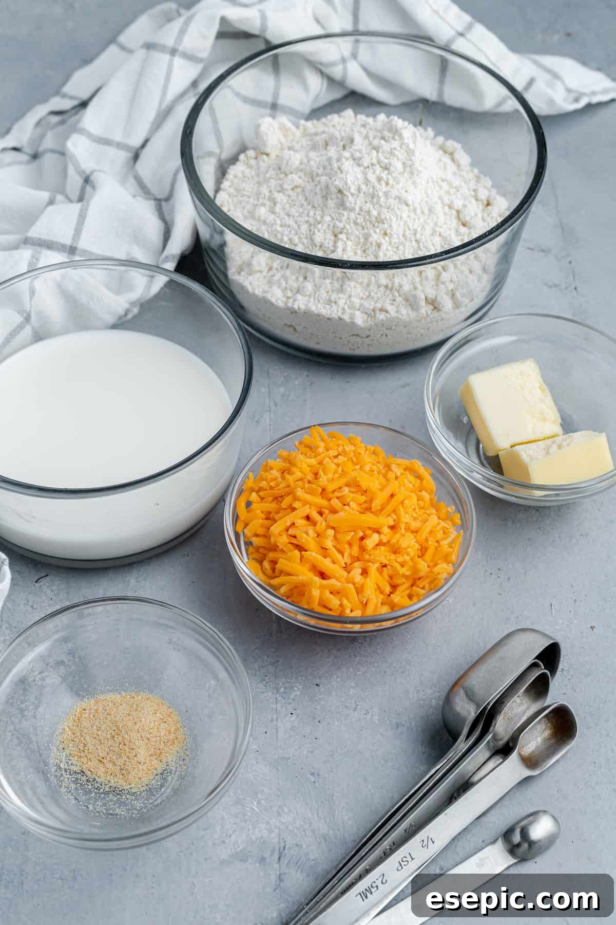 A curated display of all ingredients for the Air Fryer Red Lobster Biscuits: Bisquick, butter, garlic powder, shredded cheddar, milk, and herbs.