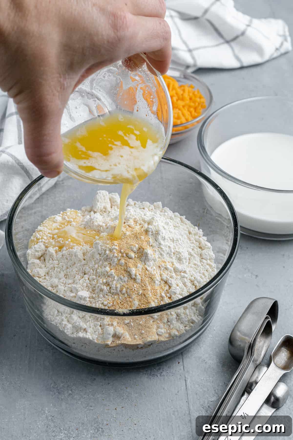 Melted butter being drizzled over a bowl of Bisquick mix, ready for stirring.