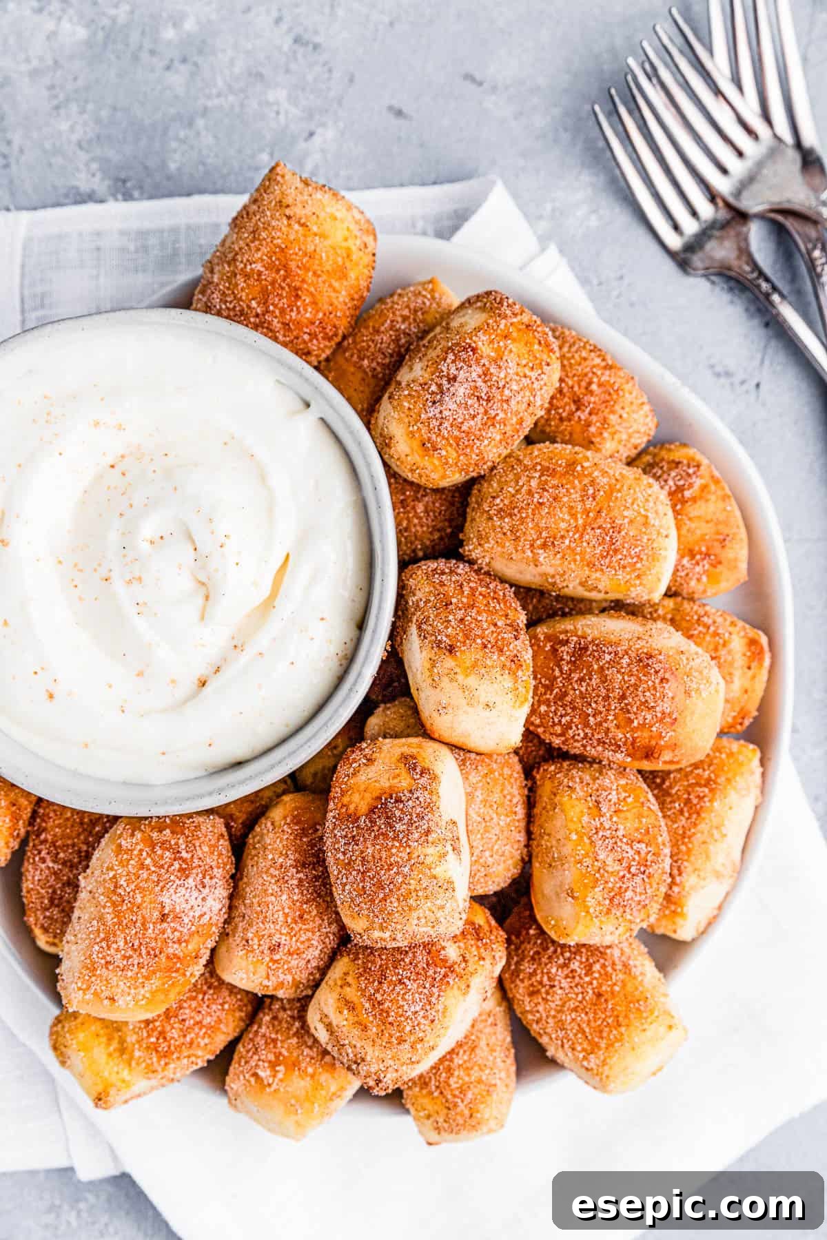 Cinnamon Sugar Pretzel Poppers 3 A plate of cinnamon sugar pretzel bites served with cream cheese dip in a small bowl
