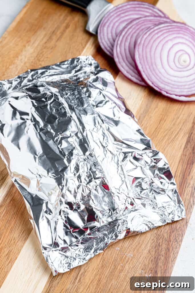 Cheeseburger Foil Dinner with Roasted Vegetables 4 Folded foil on a cutting board and stuffed with cheeseburgers