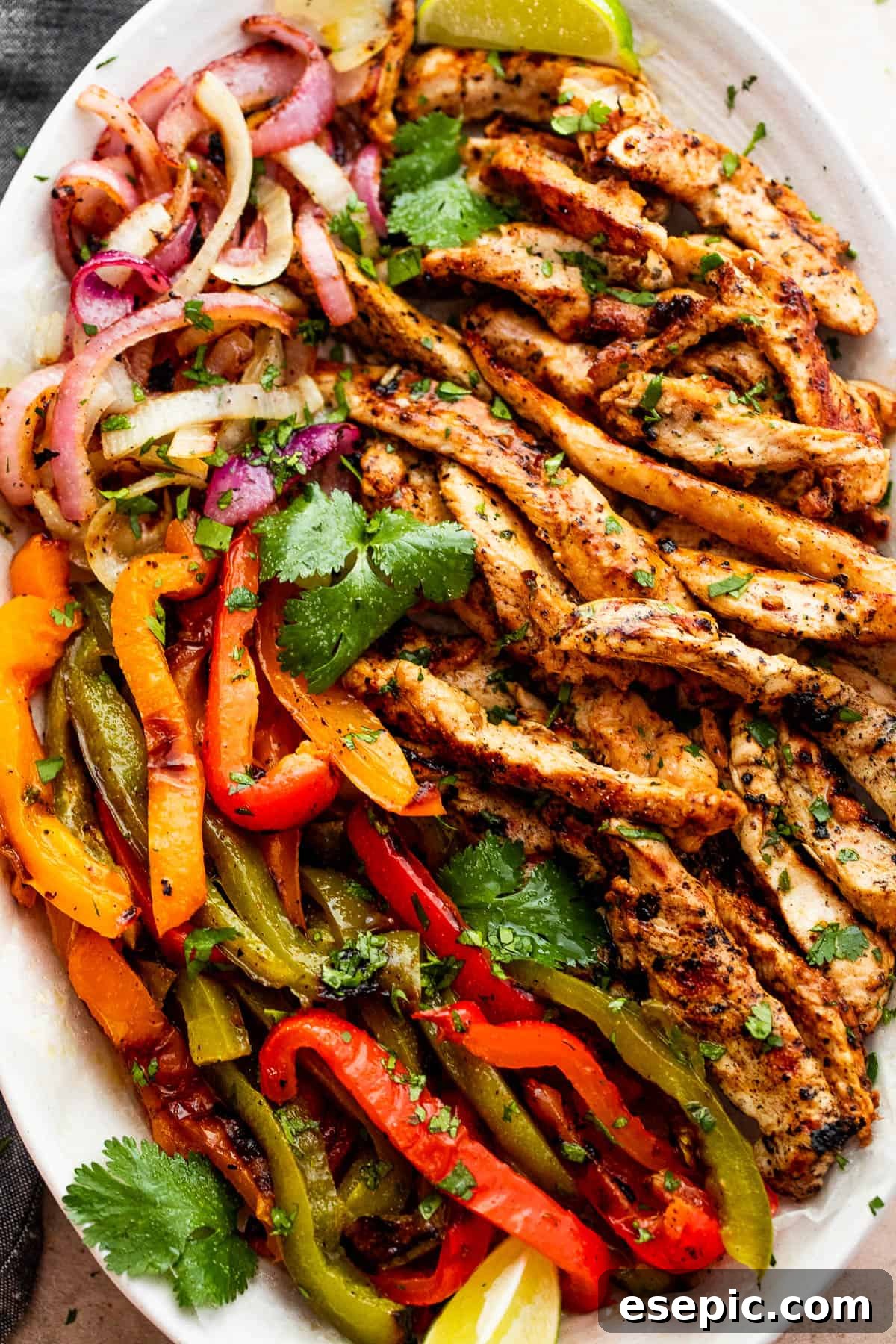 Delicious grilled chicken fajitas featuring juicy chicken, onions, and peppers, served in warm tortillas with your favorite toppings. grilled chicken strips, colorful bell pepper strips, and onions on a serving plate garnished with cilantro leaves