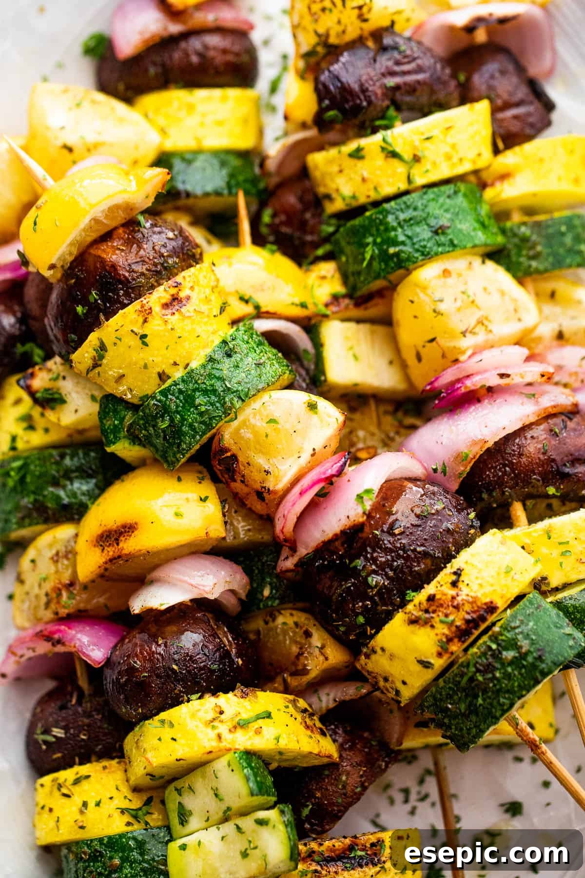 Close-up of a single plated grilled squash skewer, showing the charring on the vegetables and lemon.