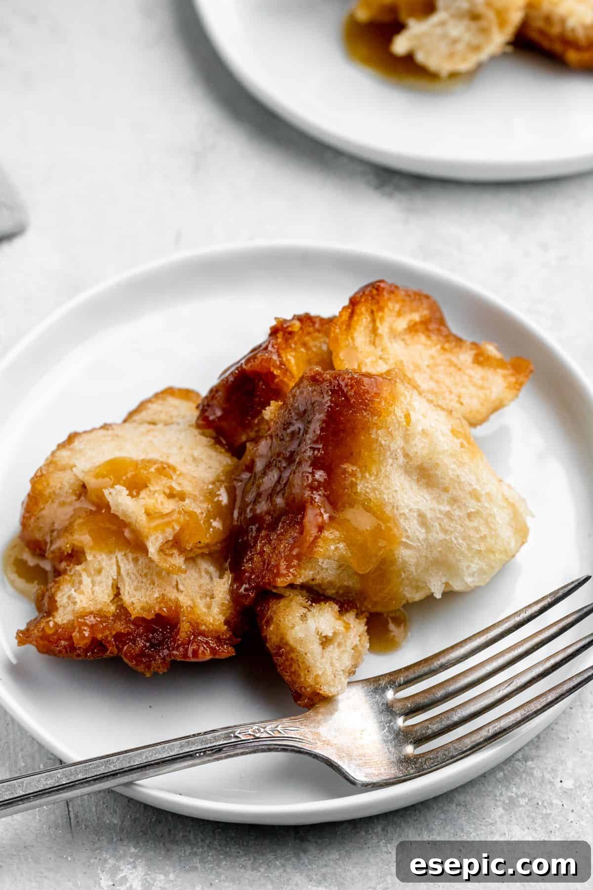 A serving of monkey bread on a dessert plate with a fork, ready to be enjoyed.