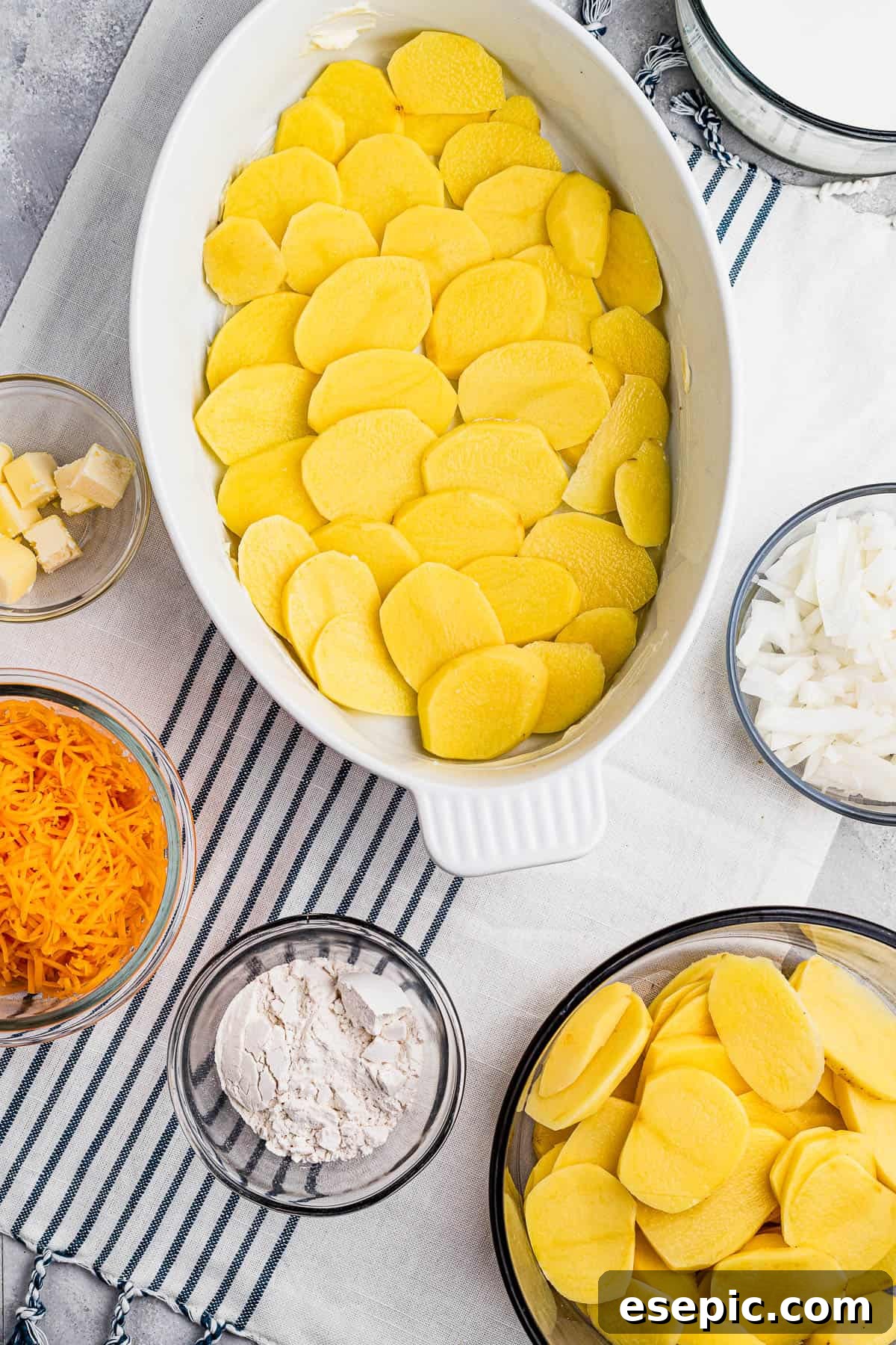 Thinly sliced potatoes carefully layered in a baking dish, creating a neat foundation for the casserole.