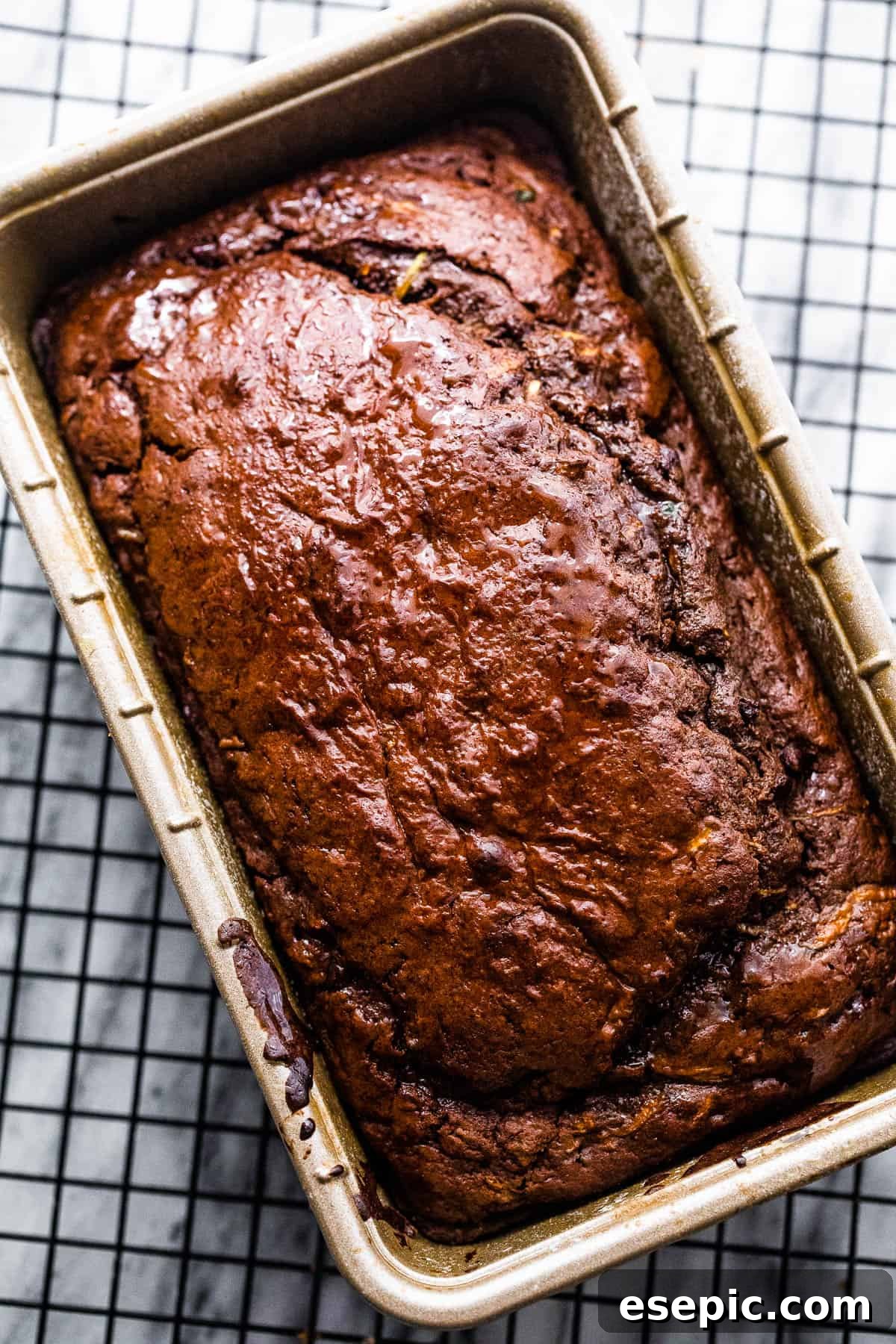 Cooked chocolate zucchini bread in a loaf pan, cooling on a wire rack, ready to be removed.