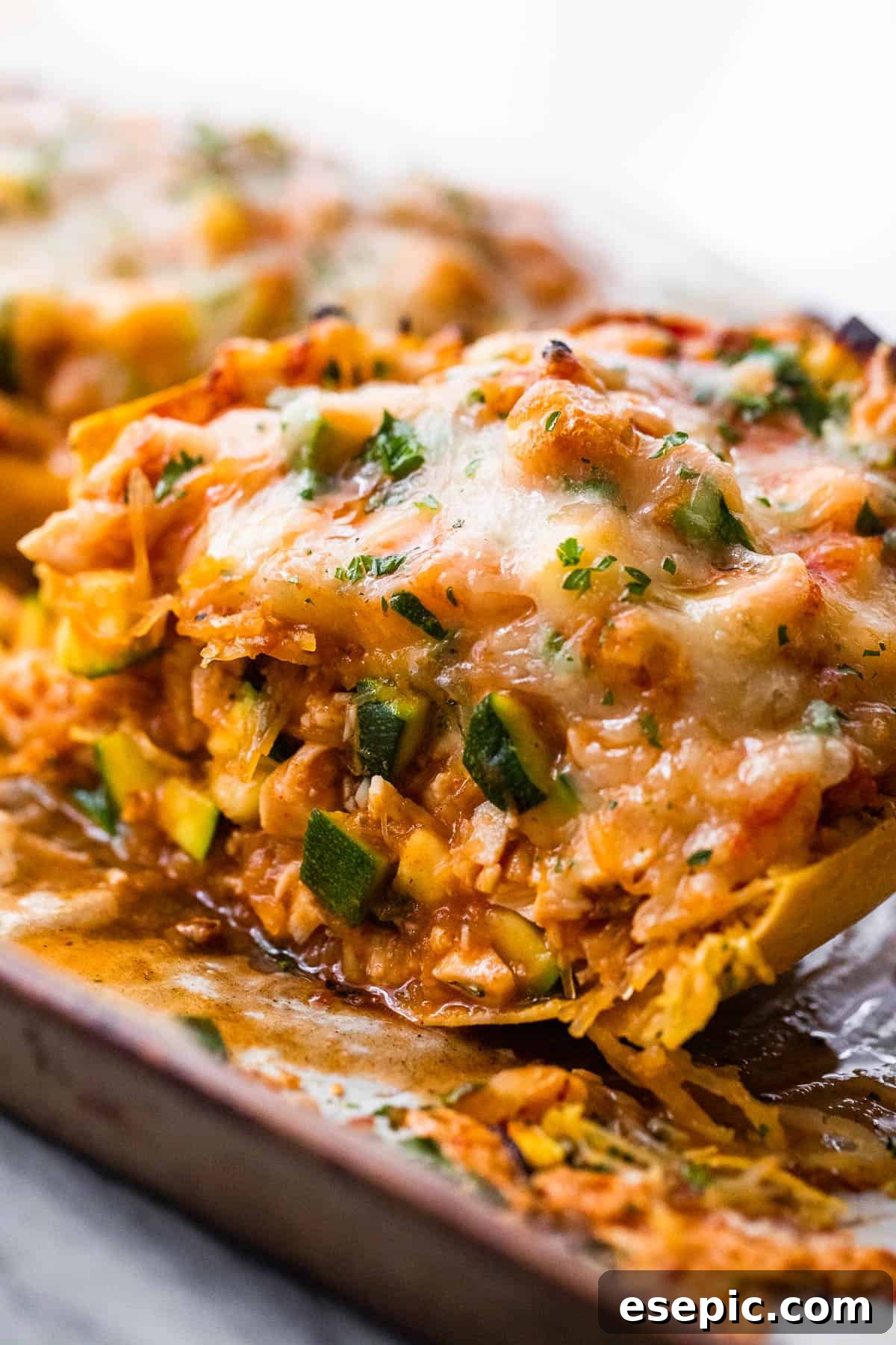 Close-up of a halved spaghetti squash boat filled with chicken enchilada mixture and melted cheese, garnished with cilantro