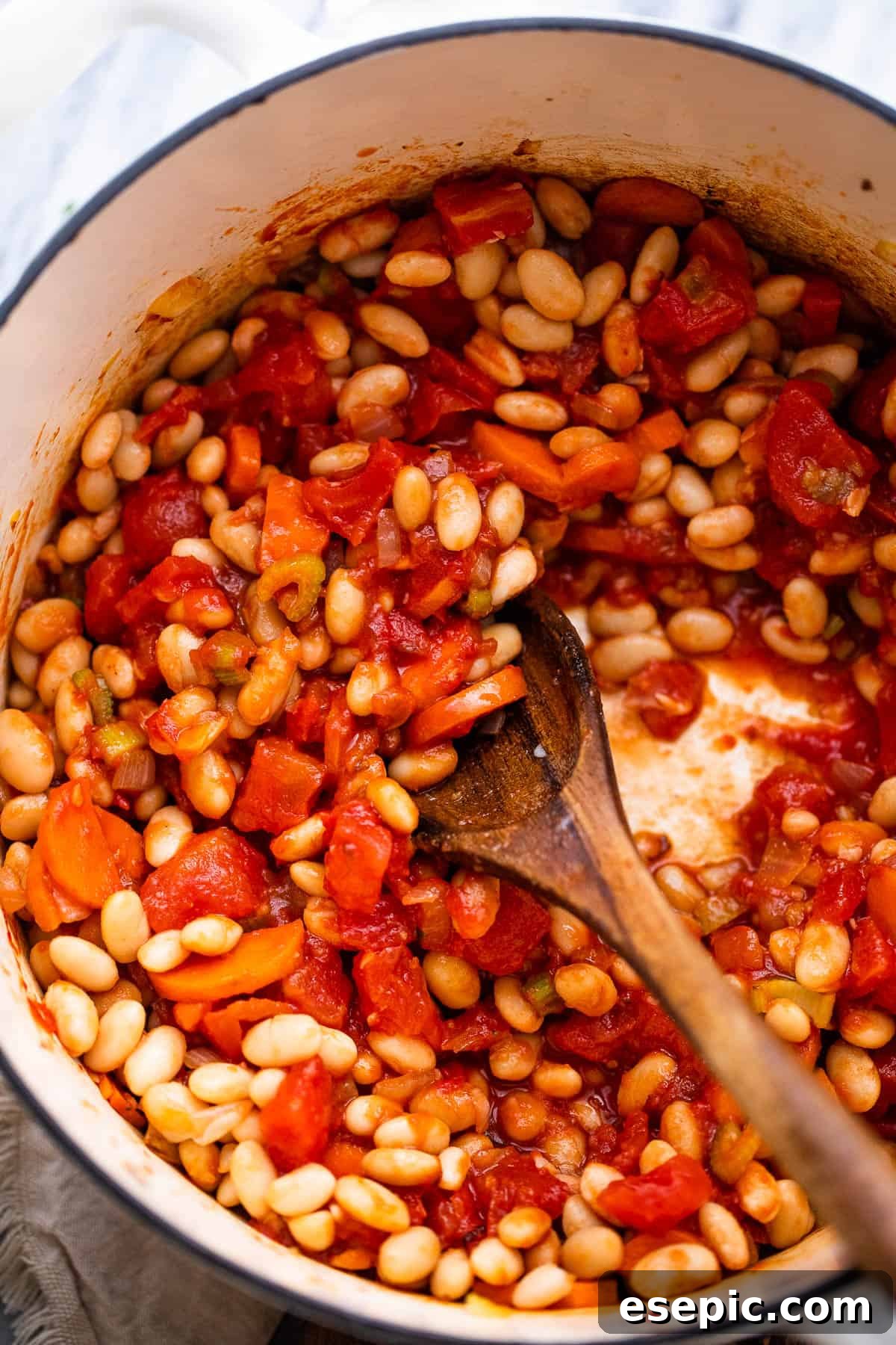 Close-up of a Dutch oven with beans and tomatoes simmering for Pasta Fagioli.