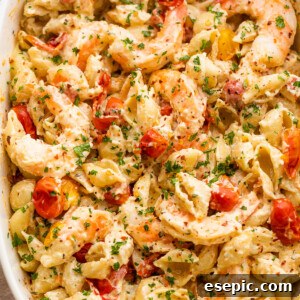 white baking dish with shrimp and pasta tossed with a cream cheese sauce and cherry tomatoes