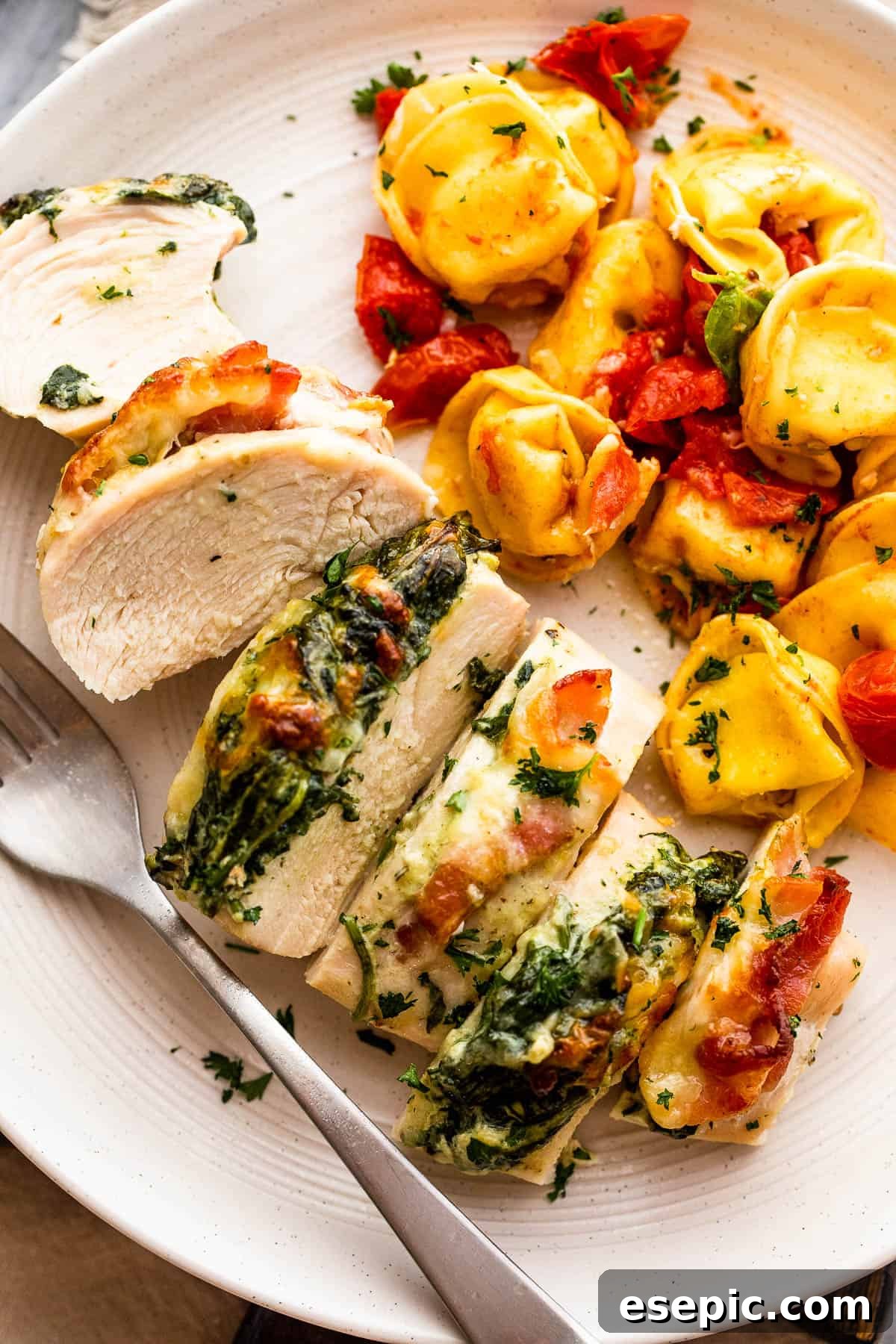 Creamy Spinach Bacon Stuffed Chicken 2 Cut up stuffed chicken breast served alongside tortellini pasta, highlighting the creamy spinach and crispy bacon filling.