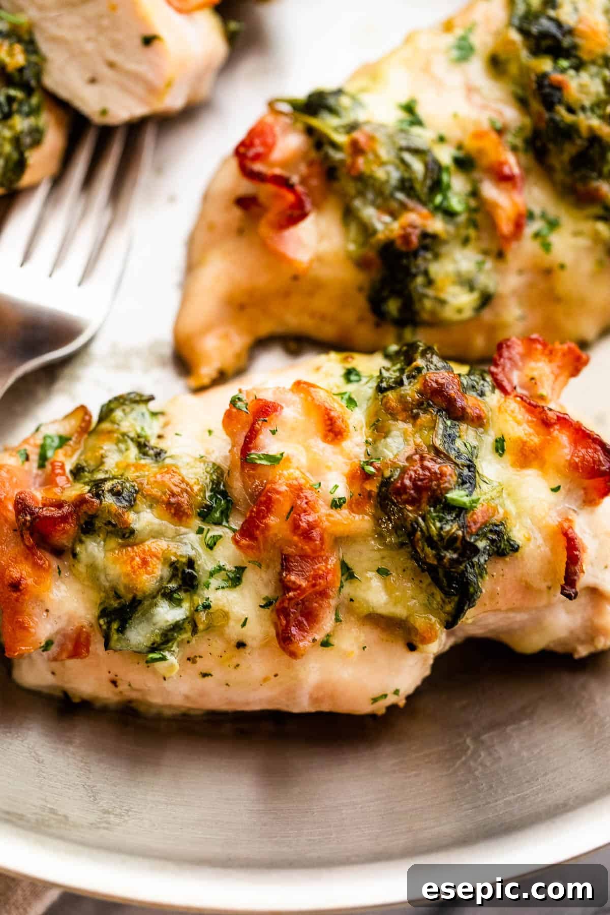 Creamy Spinach Bacon Stuffed Chicken 3 Overhead shot of a baked chicken breast stuffed with spinach and bacon, garnished with fresh herbs.
