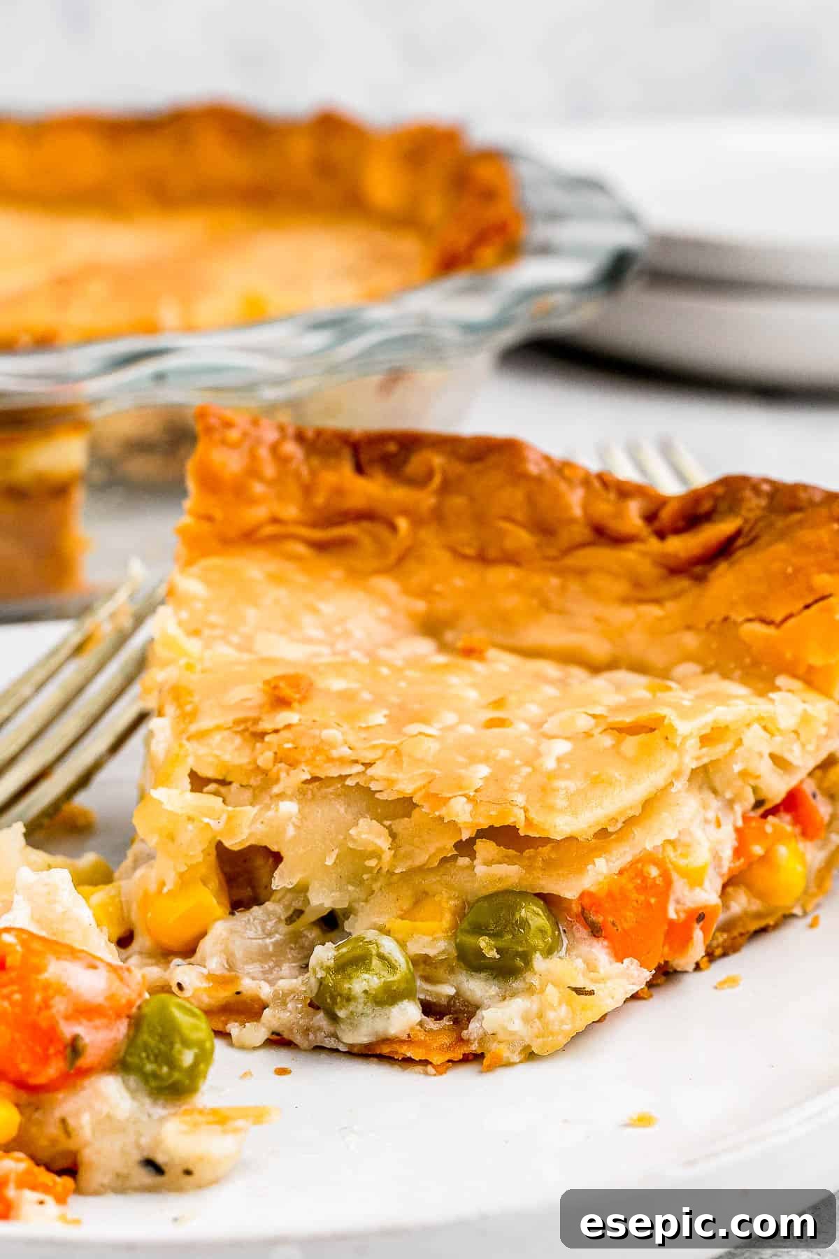 Golden Crust Chicken Delight 6 A generous slice of homemade chicken pot pie, revealing the creamy chicken and vegetable filling beneath a golden, flaky crust, resting on a white plate.