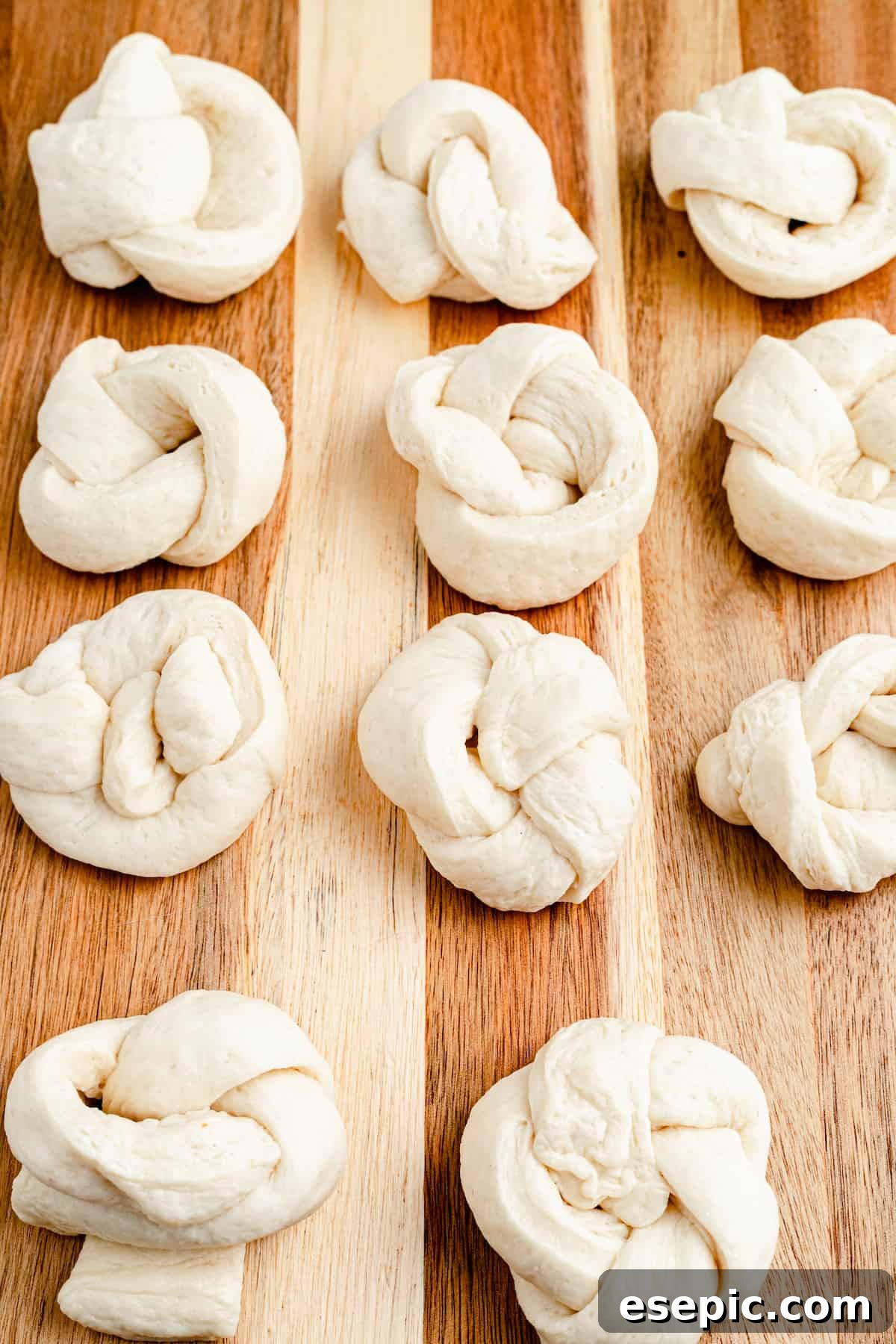 Unbaked and unseasoned strips of pizza dough, shaped into knots on a work surface.