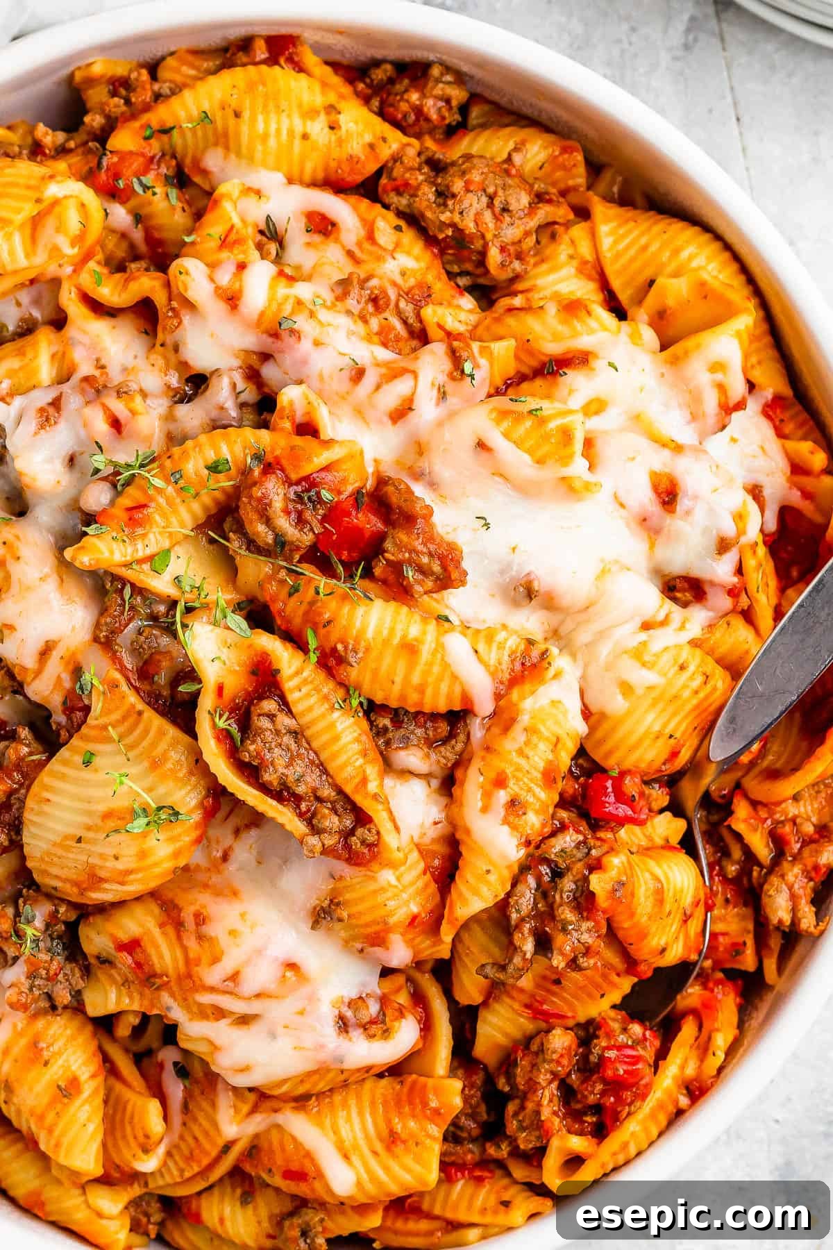 Instant Pot Hearty Beef and Shells 2 A serving dish filled with cooked pasta shells and ground beef in tomato sauce, topped with melted mozzarella.