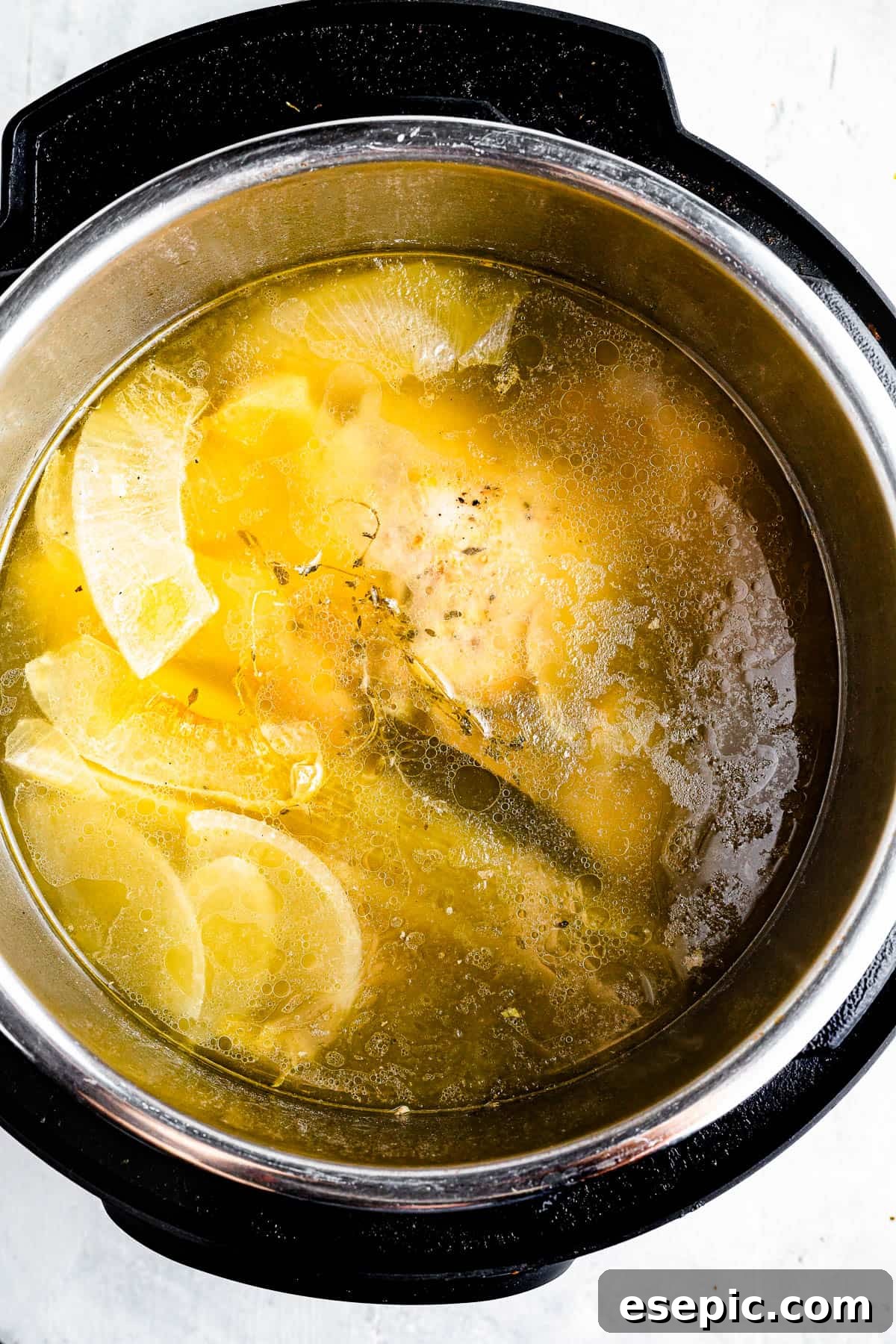 An overhead shot of the interior of an Instant Pot, filled with fragrant chicken broth, a perfectly cooked whole chicken, and tender scraps of vegetables, ready for straining.