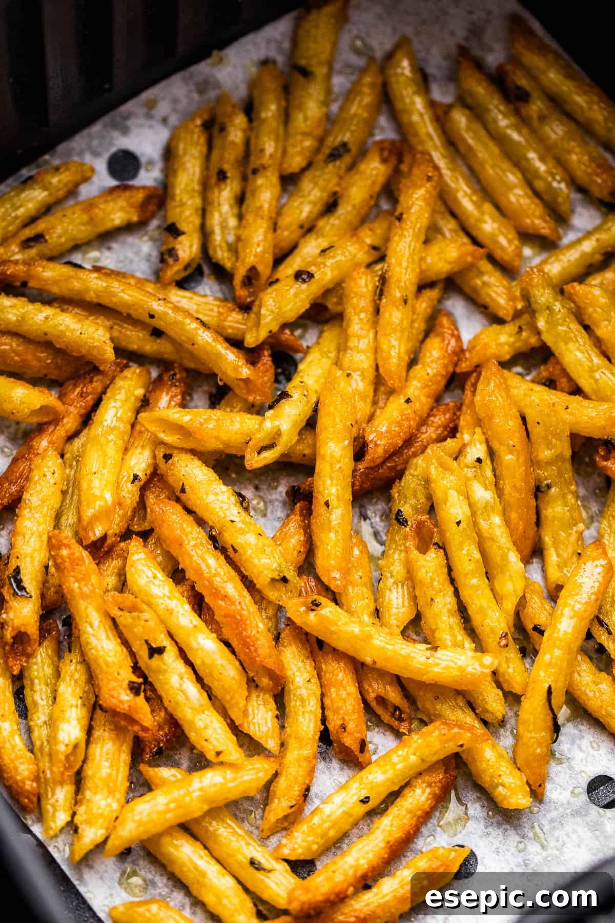 Crispy Pasta Chips Air Fry or Bake 5 Close-up view of golden-brown, crispy baked pasta chips resting inside an air fryer basket, ready to be served.