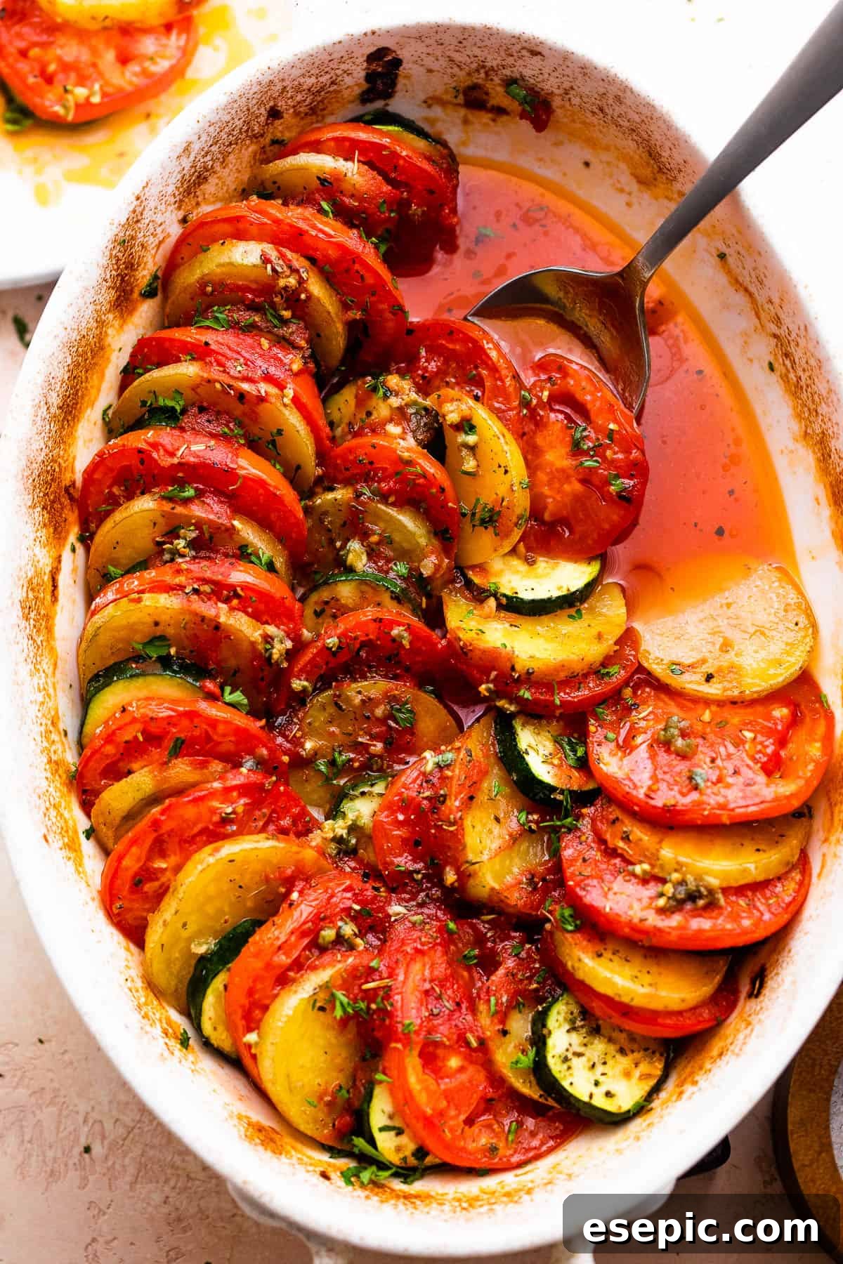 overhead shot of zucchini, tomato, and potato slices arranged accordion style in a baking dish.