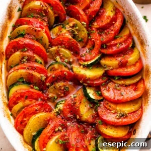 overhead shot of zucchini, tomato, and potato slices arranged accordion style in a baking dish.