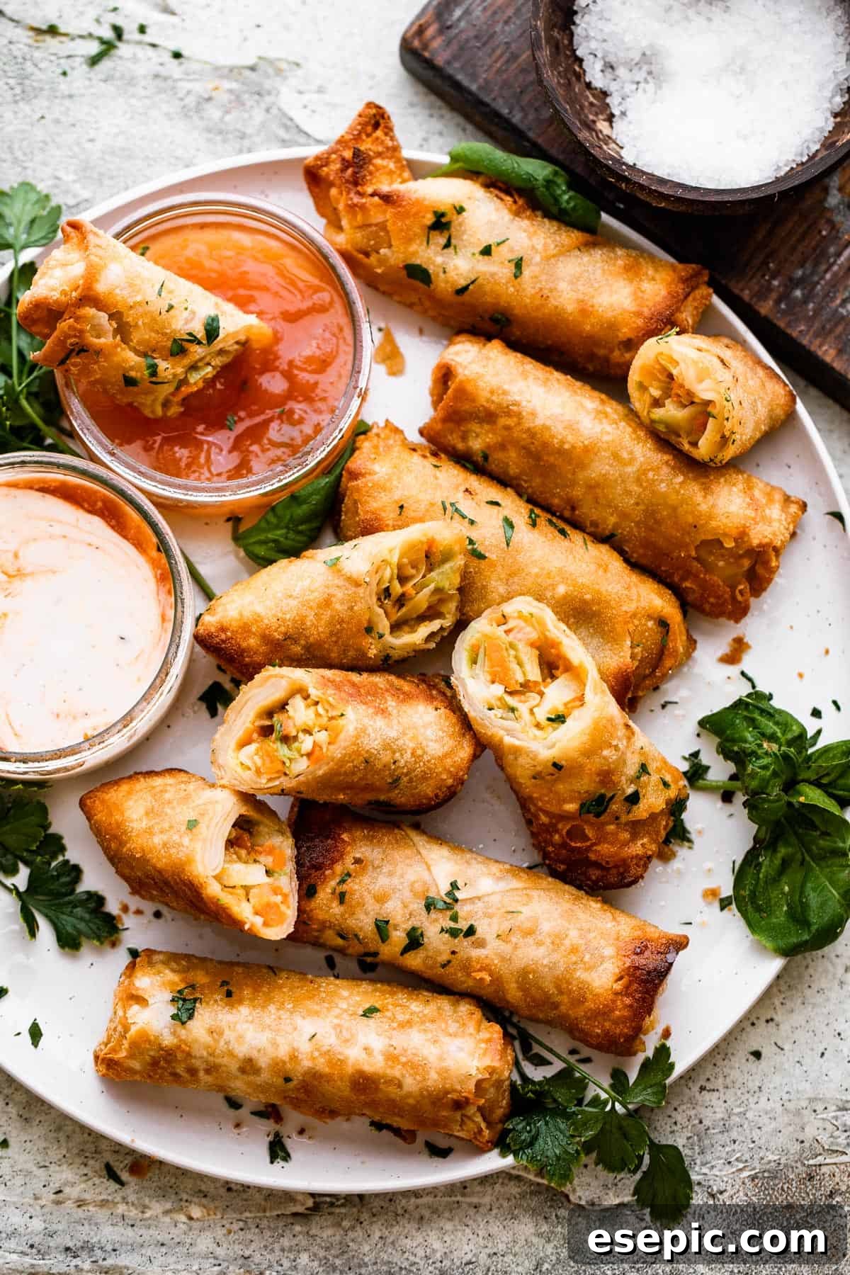 A beautifully arranged plate of golden veggie spring rolls, served with a vibrant dipping sauce, ready to be enjoyed.