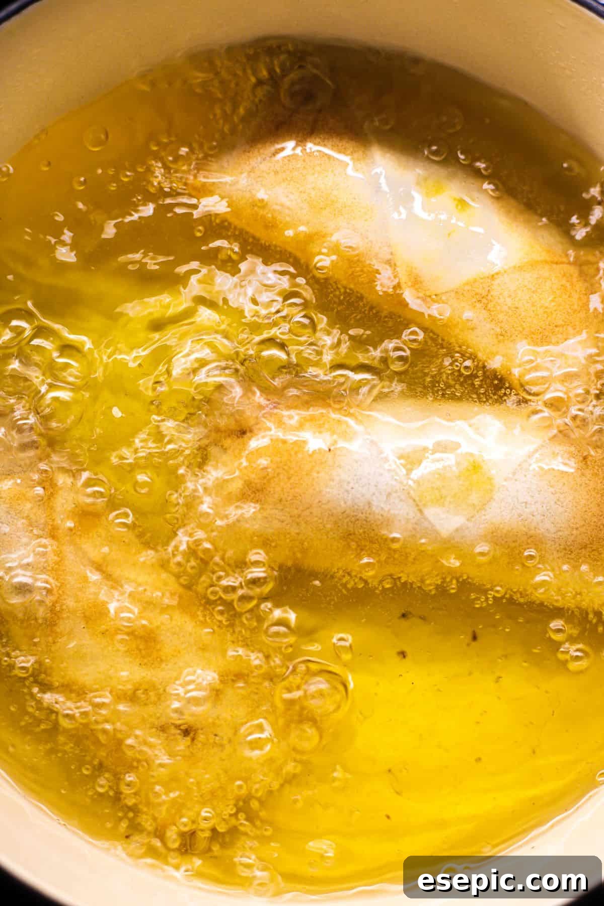 Several crispy spring rolls are being carefully deep-fried in a hot skillet, bubbling gently in the oil as they turn golden brown.