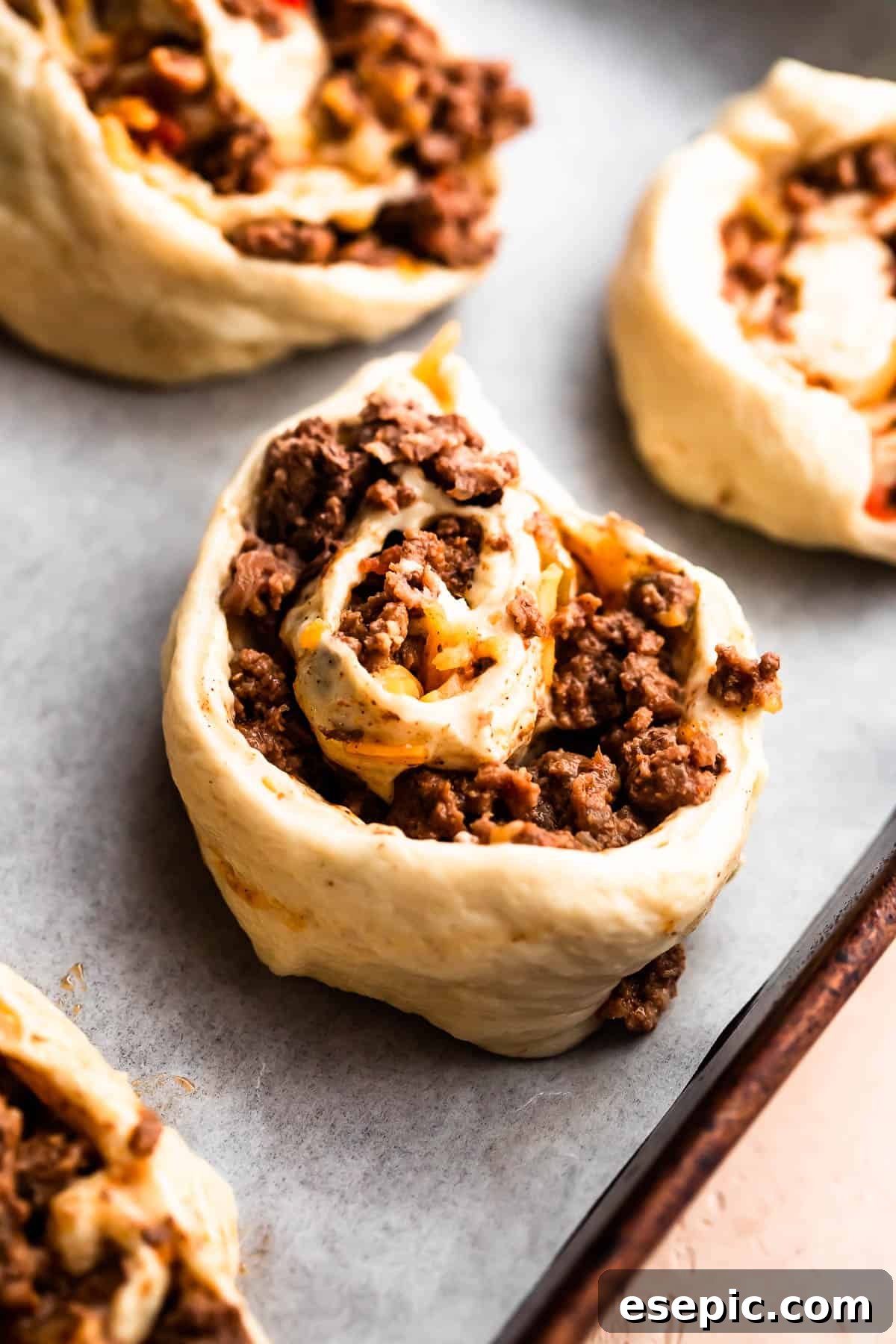 Cheesy Baked Taco Swirls 5 Ground beef and cheese rolled up in pizza dough, cut into perfect pinwheels on a cutting board.