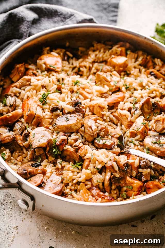 Chicken, mushrooms, and rice in a pan being stirred, highlighting the creamy texture and rich ingredients.