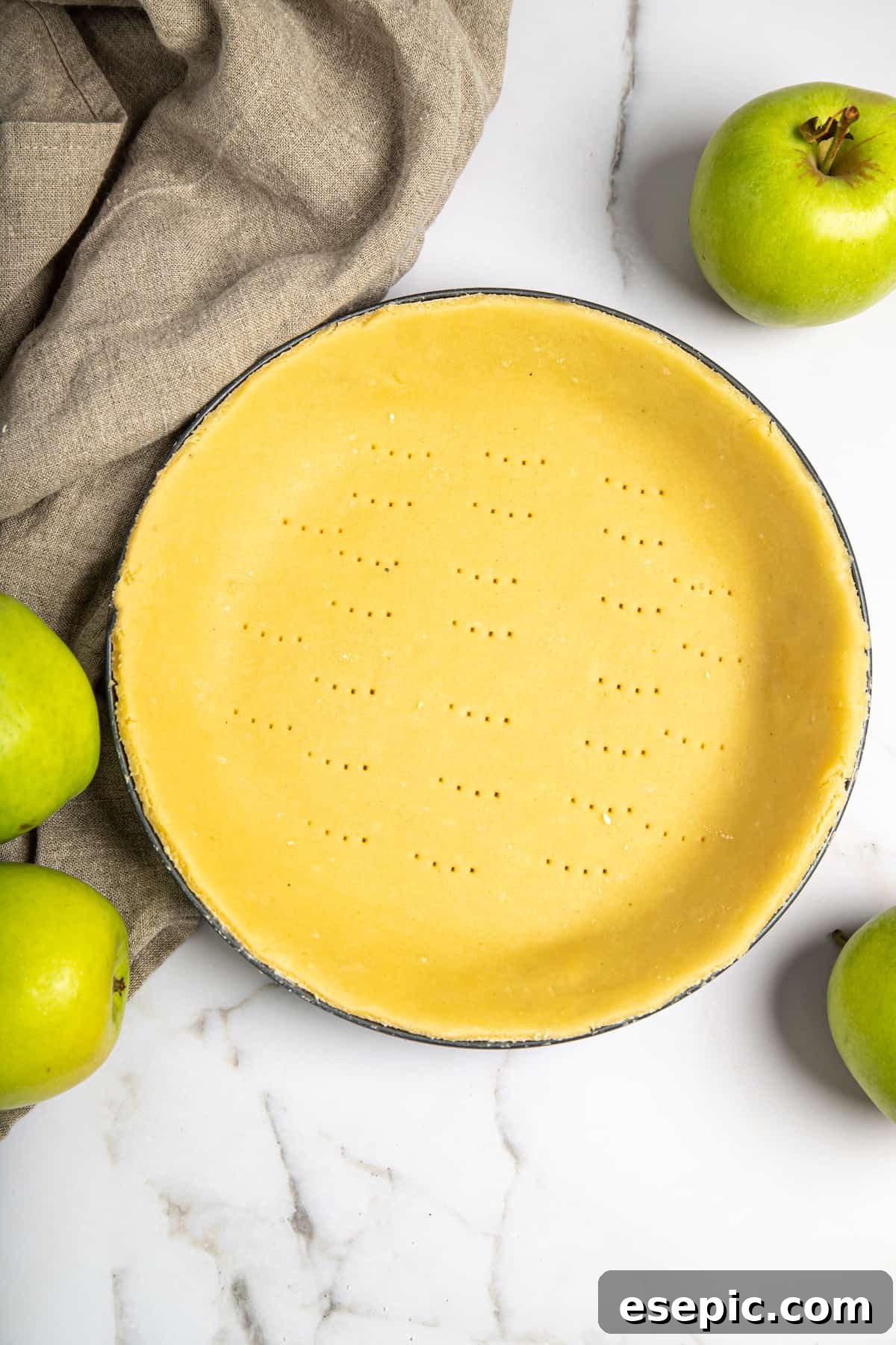 This classic yet easy and delicious Apple Pie recipe is made from scratch, with a buttery, flaky pie crust, fresh apple slices, pie spices, and brown sugar. A prepared pie shell, rolled out and placed neatly into a pie plate, ready for filling.