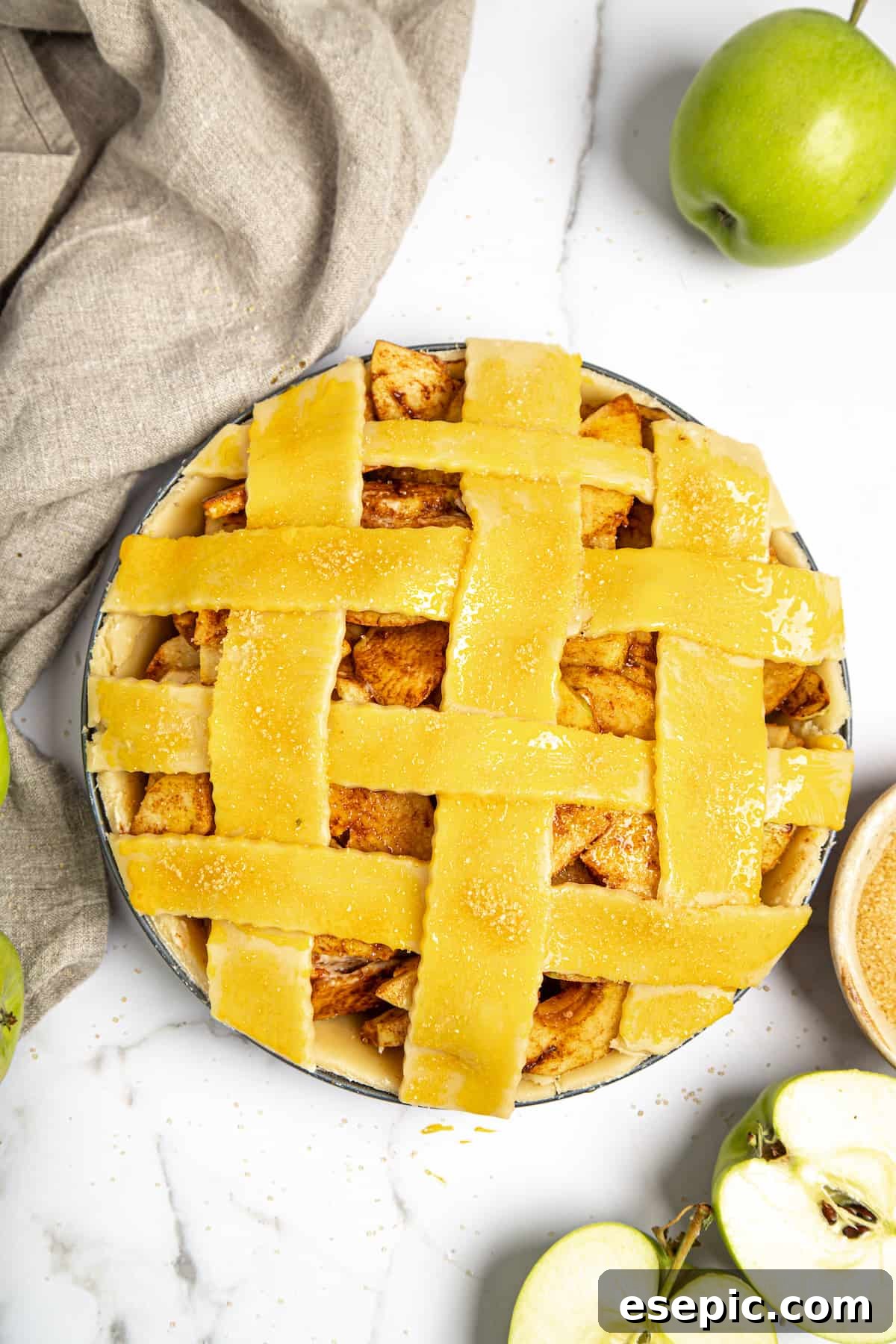 This classic yet easy and delicious Apple Pie recipe is made from scratch, with a buttery, flaky pie crust, fresh apple slices, pie spices, and brown sugar. An unbaked apple pie with a beautifully woven lattice top, ready for the oven.